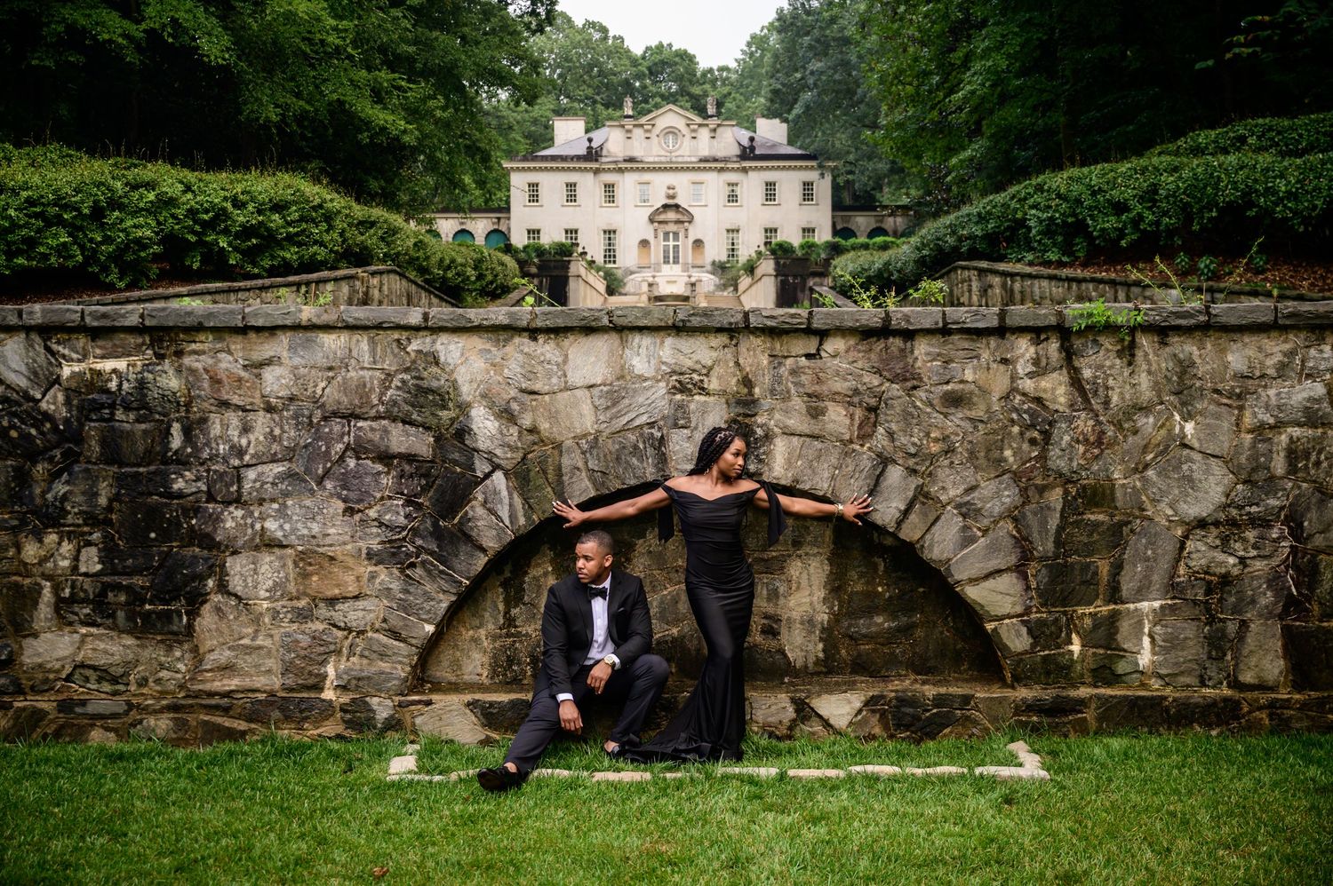 Panoramic view of a historic stone building with arched architecture and manicured grounds.