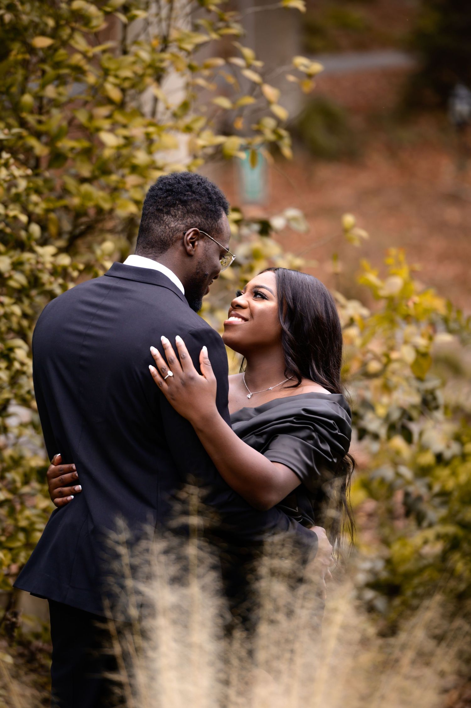 A romantic couple embraces in a natural setting with golden autumn leaves in the background.