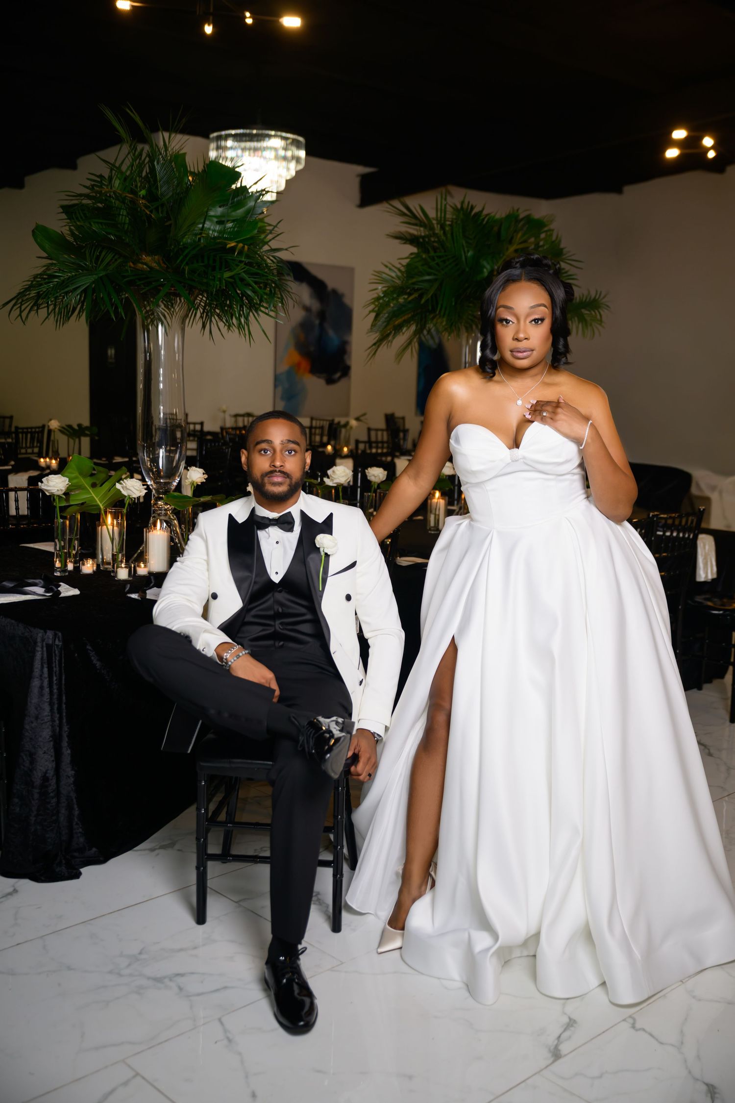 A wedding couple poses together in a black and white formal attire during their reception celebration.