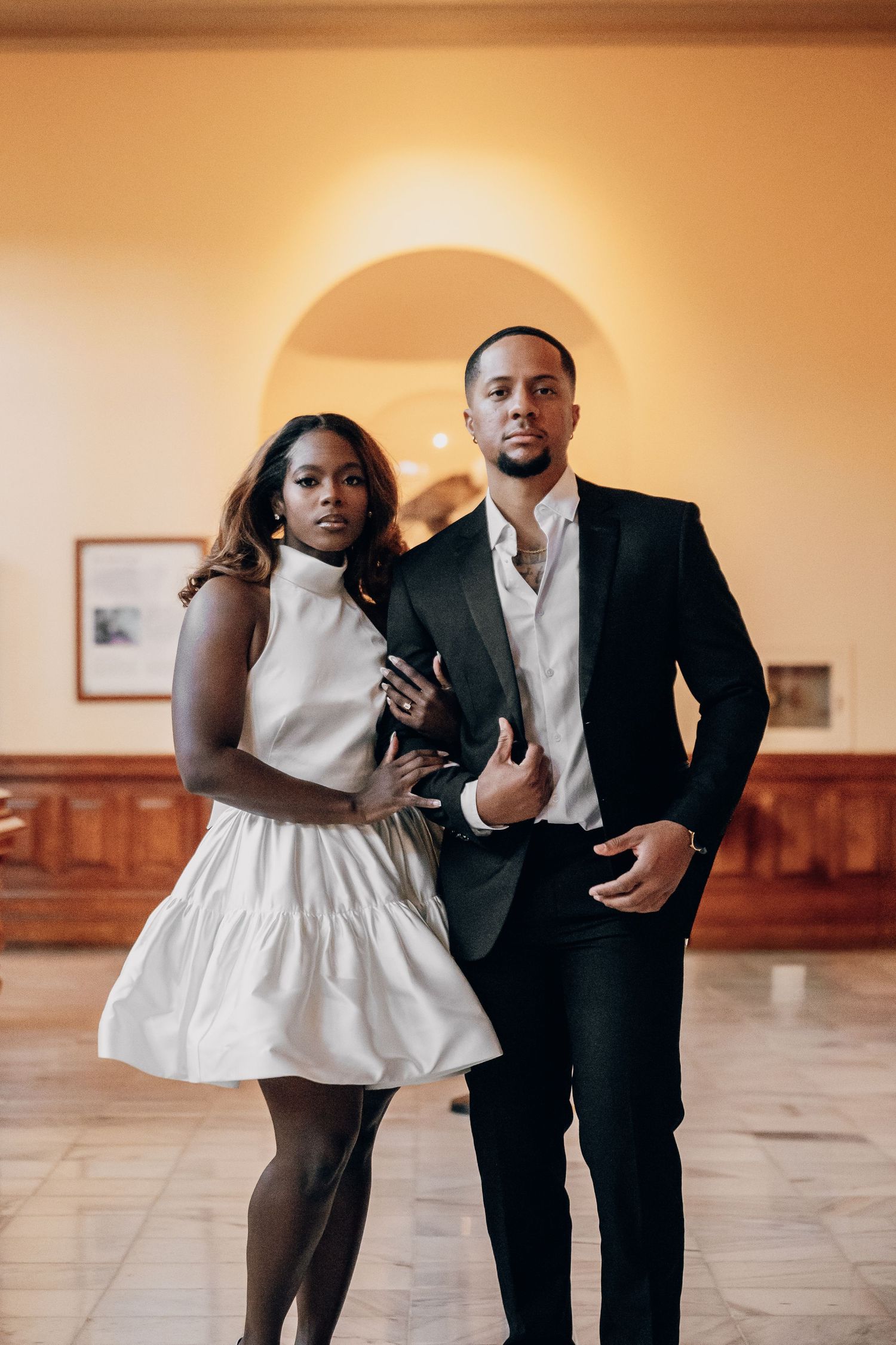 Playful dance sequence in formal attire against warm-toned interior setting.