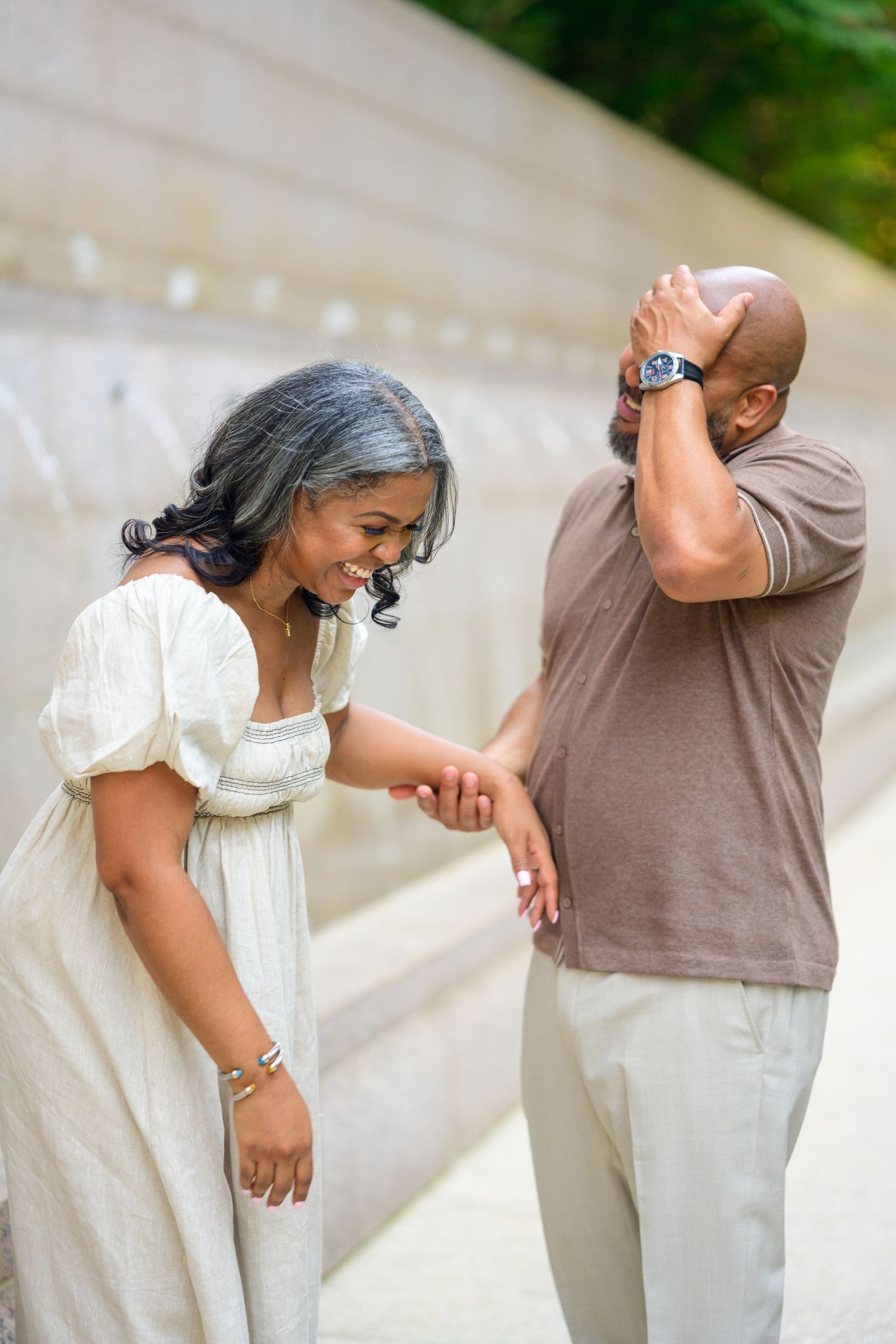 Playful couple laughing and dancing together on outdoor stone steps.