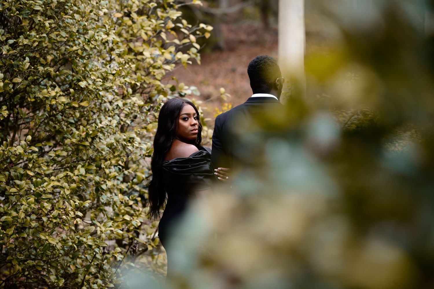 A couple shares a romantic moment among autumn foliage and stone steps during an engagement photoshoot.