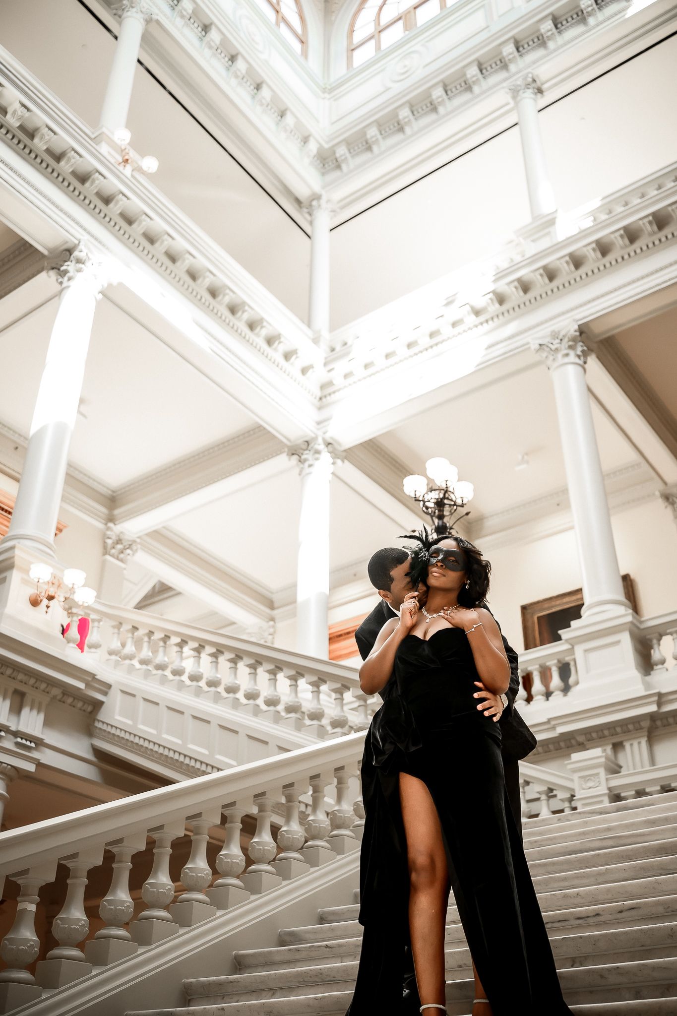 Elegant dance poses captured on grand white marble staircase with dramatic lighting.
