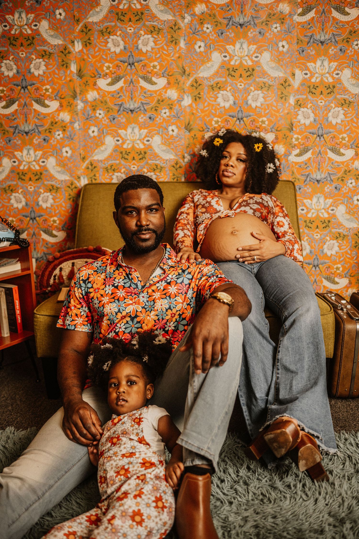 Family portrait session with retro 70s aesthetic featuring orange floral wallpaper and plush carpet.