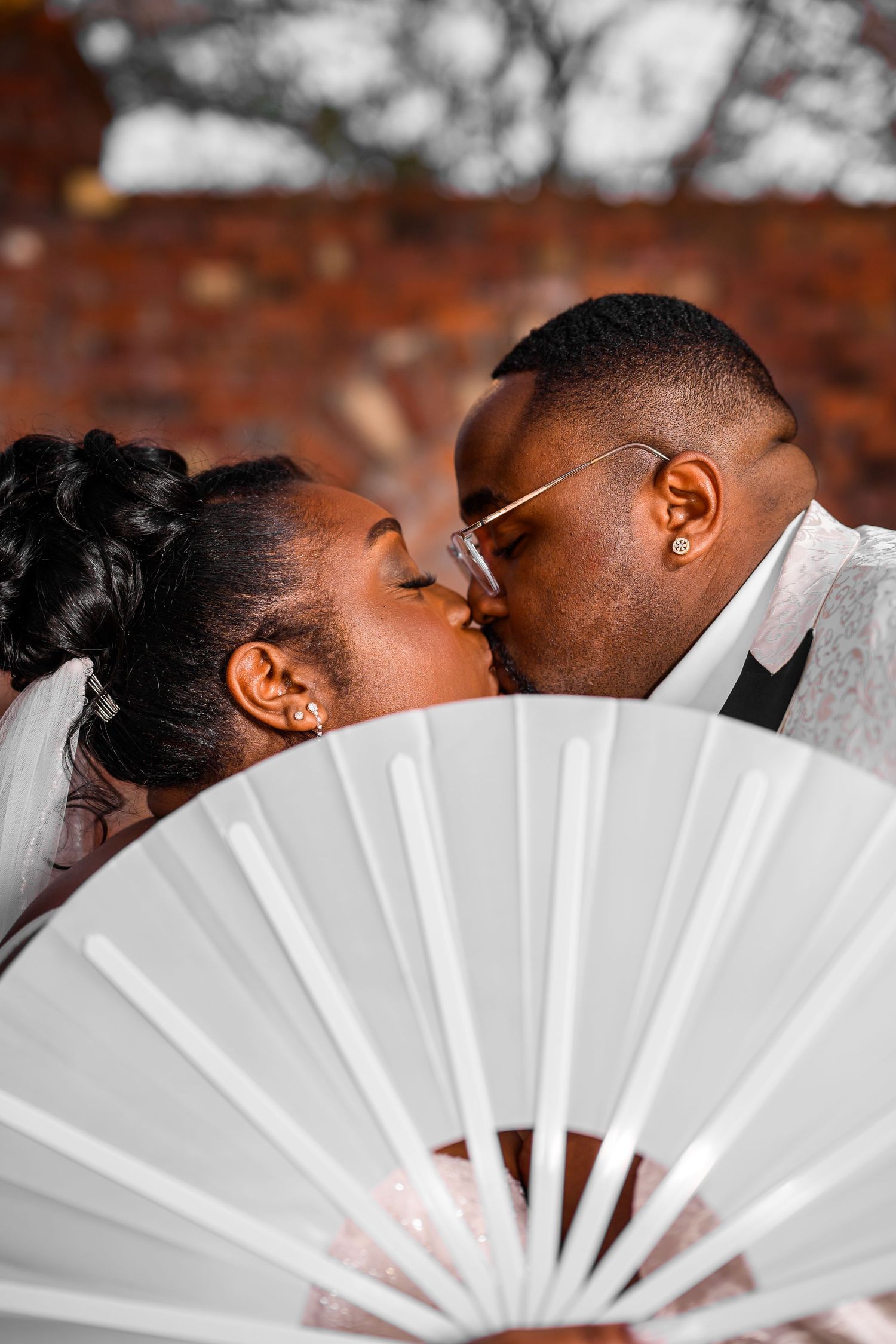 Creative wedding portrait with white decorative fan creating romantic composition.