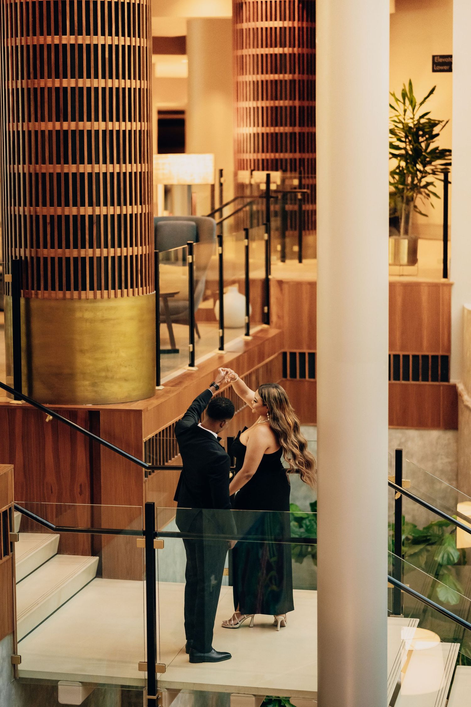 Formal couple sharing a moment near decorative columns in an elegant indoor space.