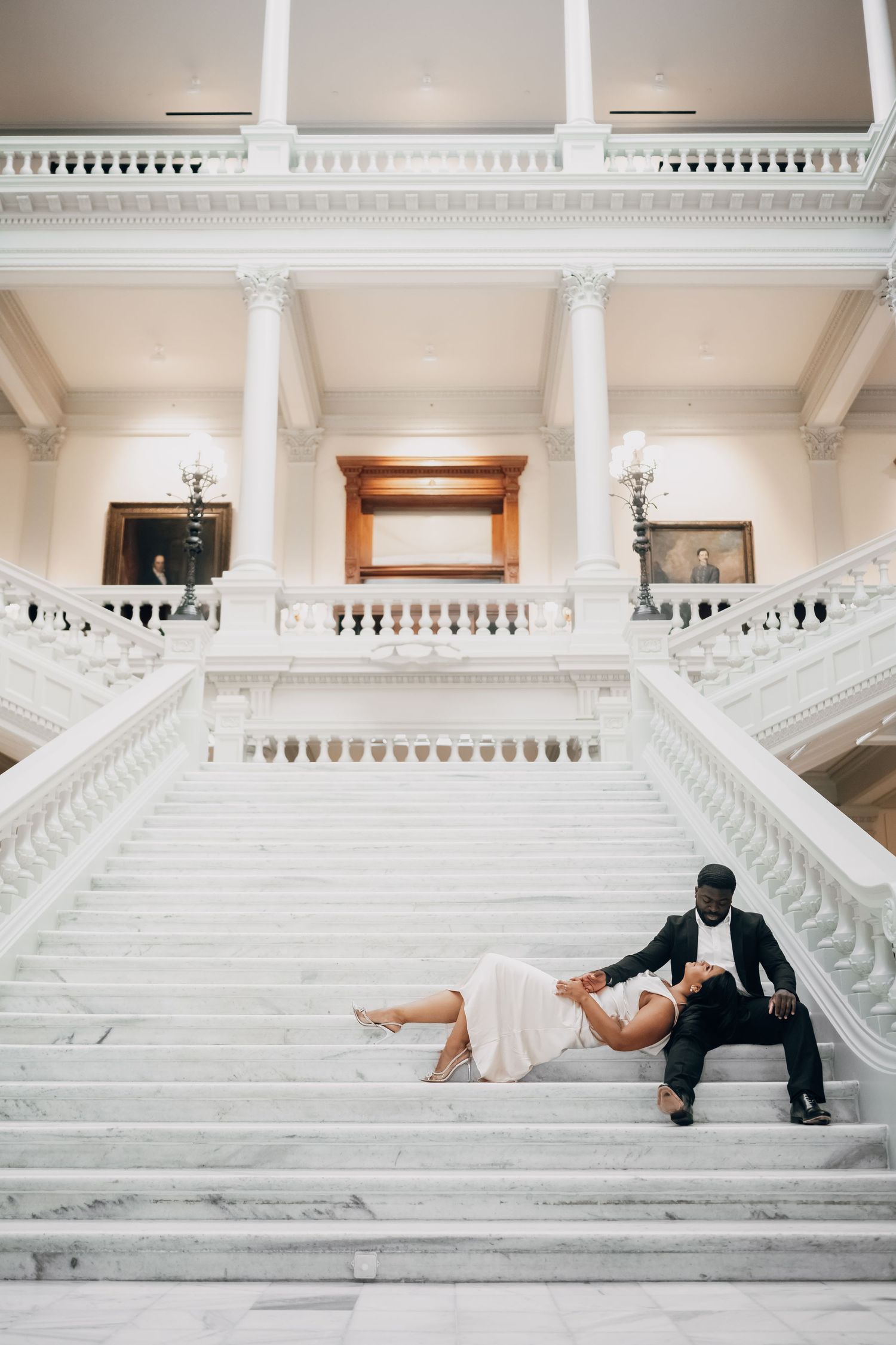 Artistic wedding photo shoot on grand white marble stairs in a classical building.