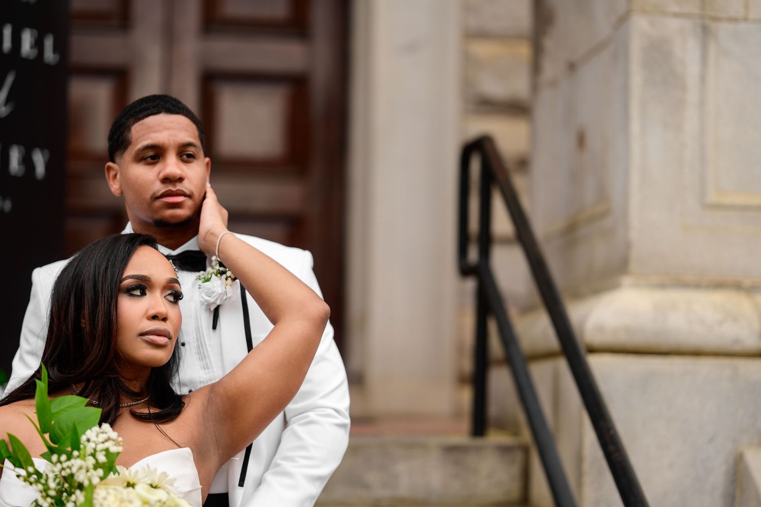 Bride and groom share intimate moments against stone building facade.