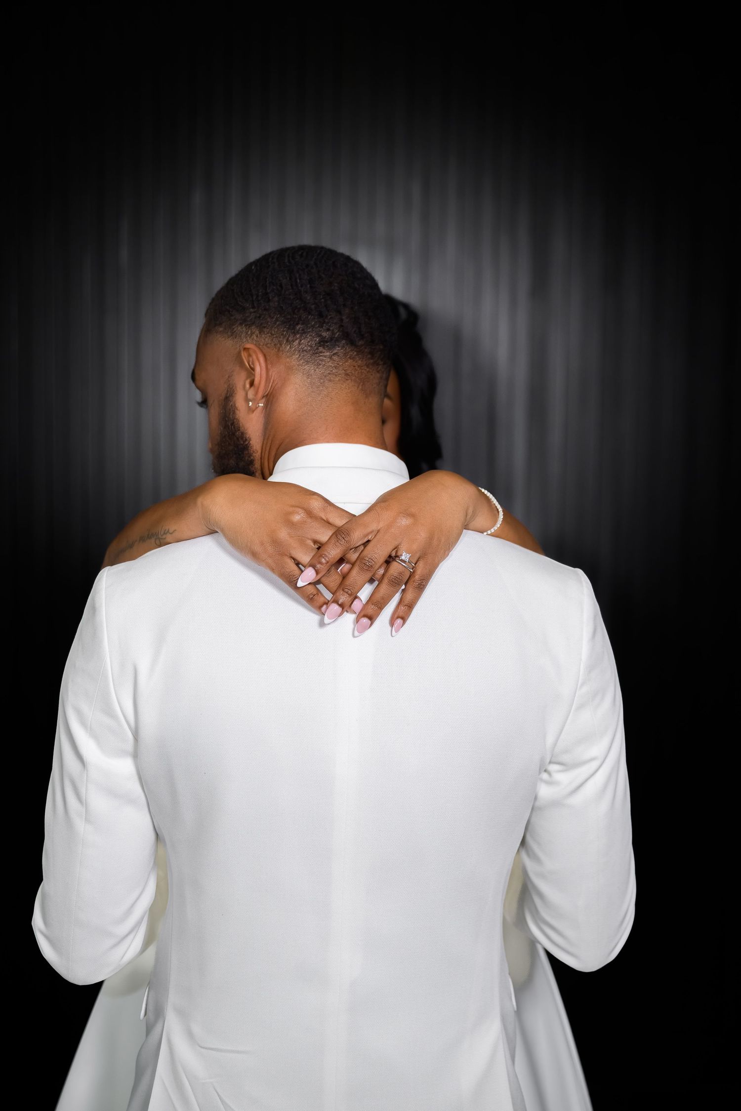 A sequence showing a person in a white shirt from behind with hands on their neck in a dark setting.