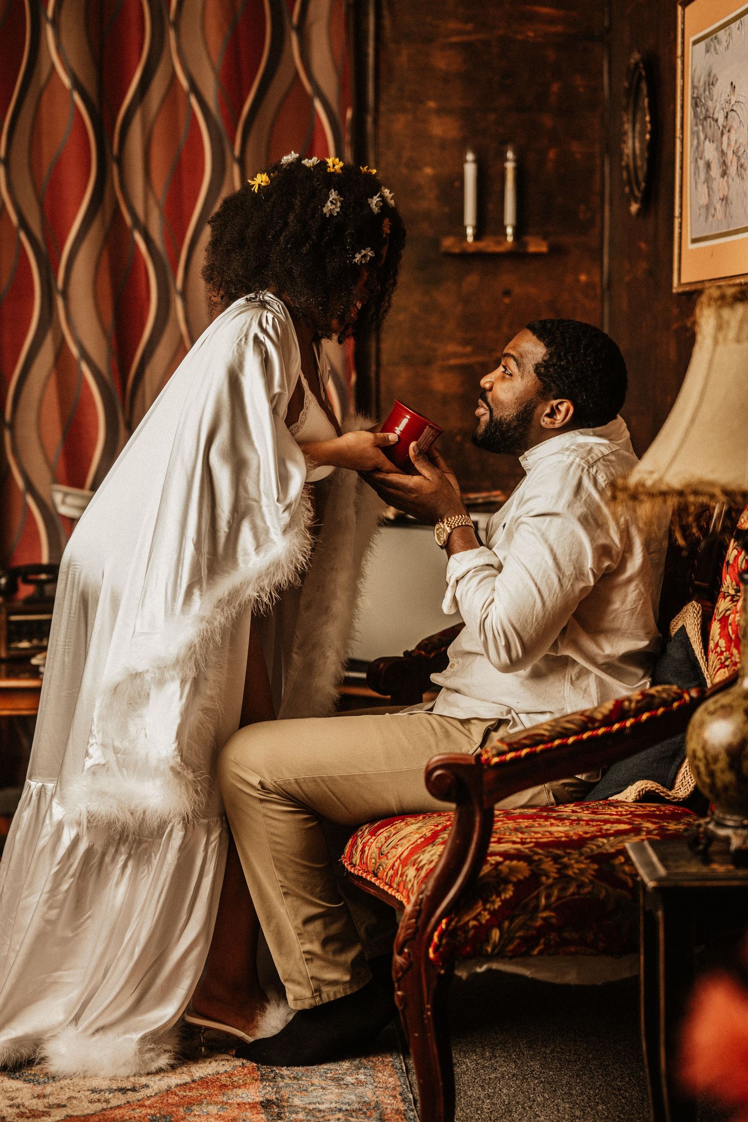 Romantic couple photoshoot in vintage setting with ornate furniture and warm lighting.