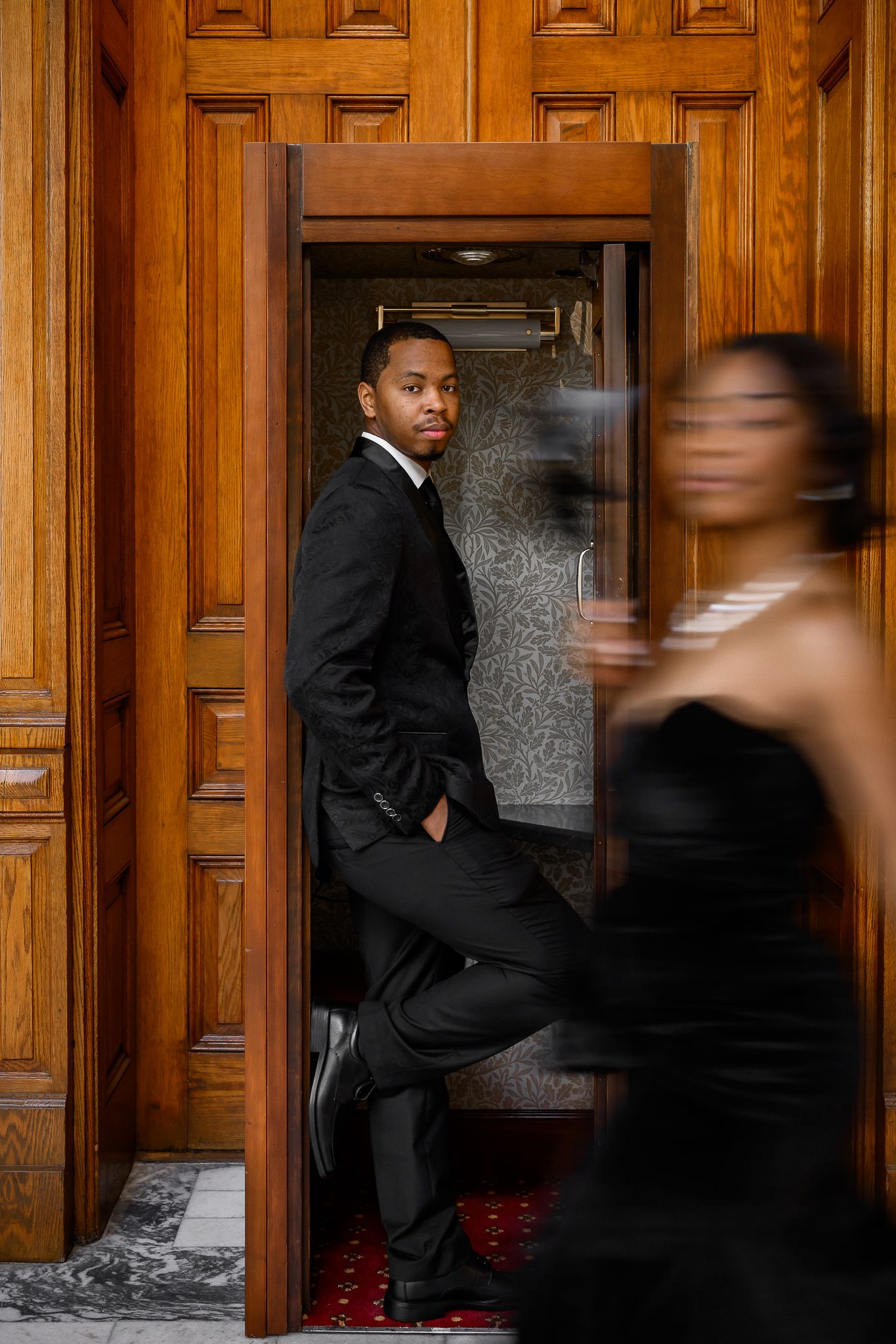 Artistic motion blur photo of couple in formal wear by ornate wooden doorway.