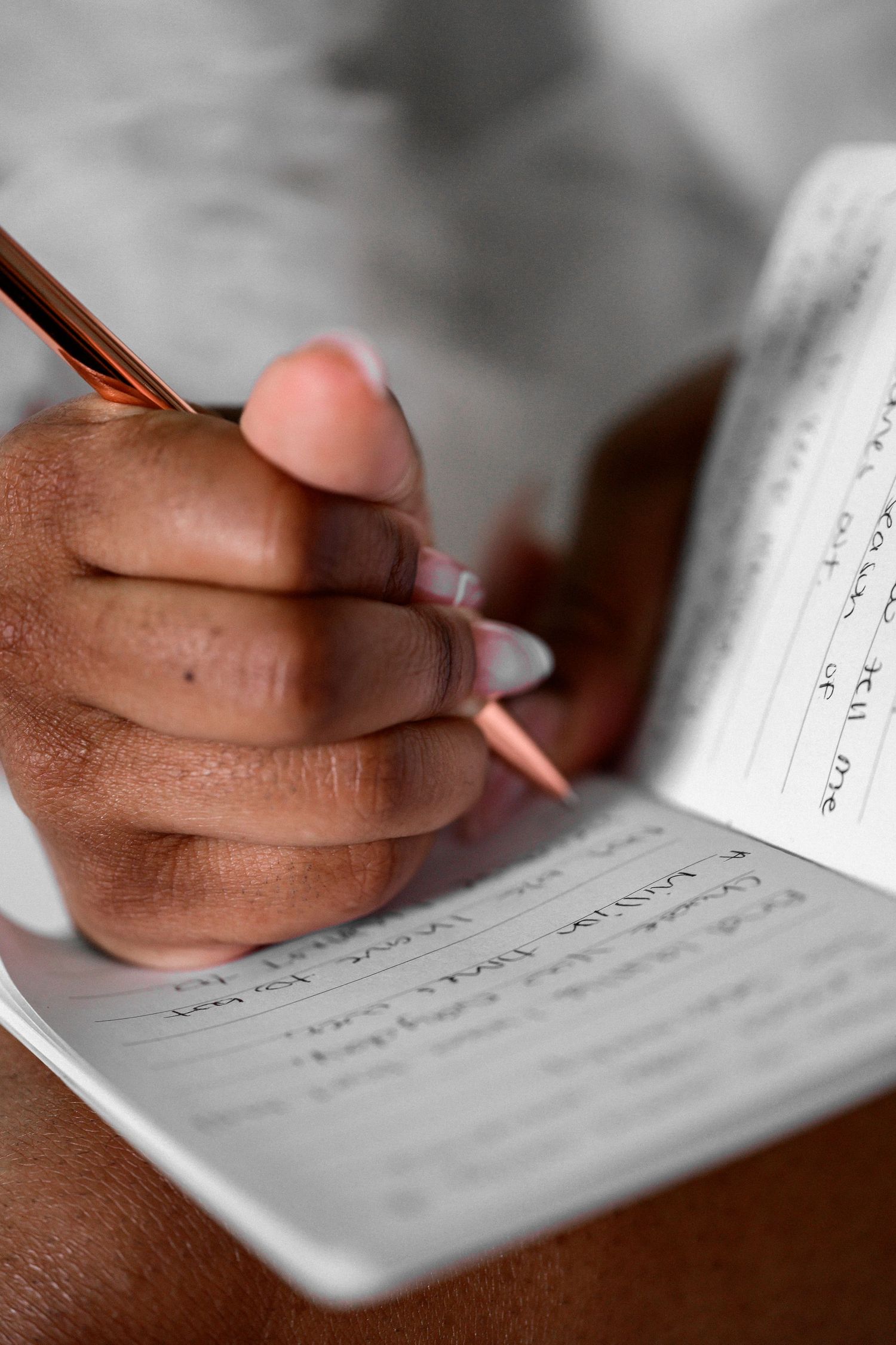 Close-up shot of hands writing on white paper with a pen.