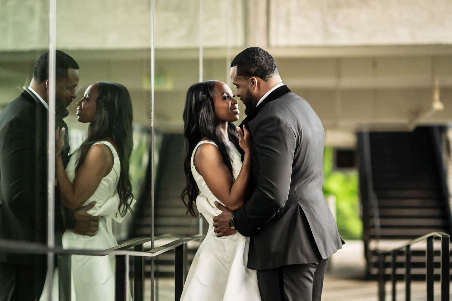 A tender embrace between a couple reflected in mirrored walls of a modern building.