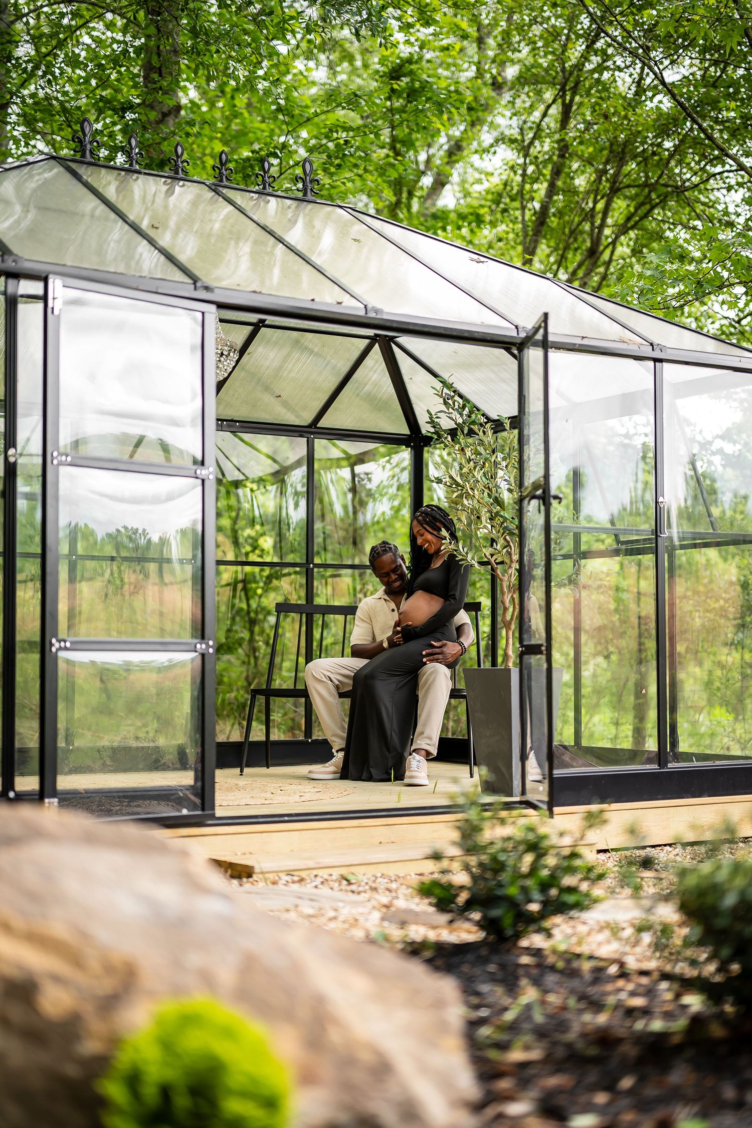 Wide angle view of a modern glass greenhouse structure nestled among trees.