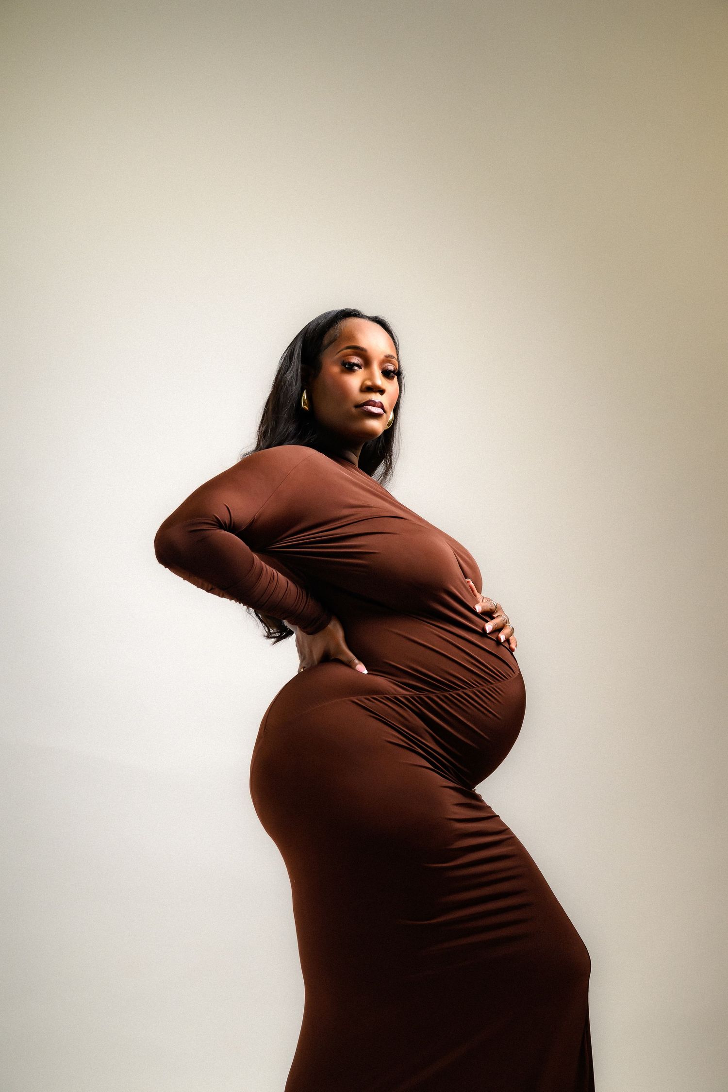 Dramatic side profile maternity shots showcasing pregnancy in brown fitted dress.