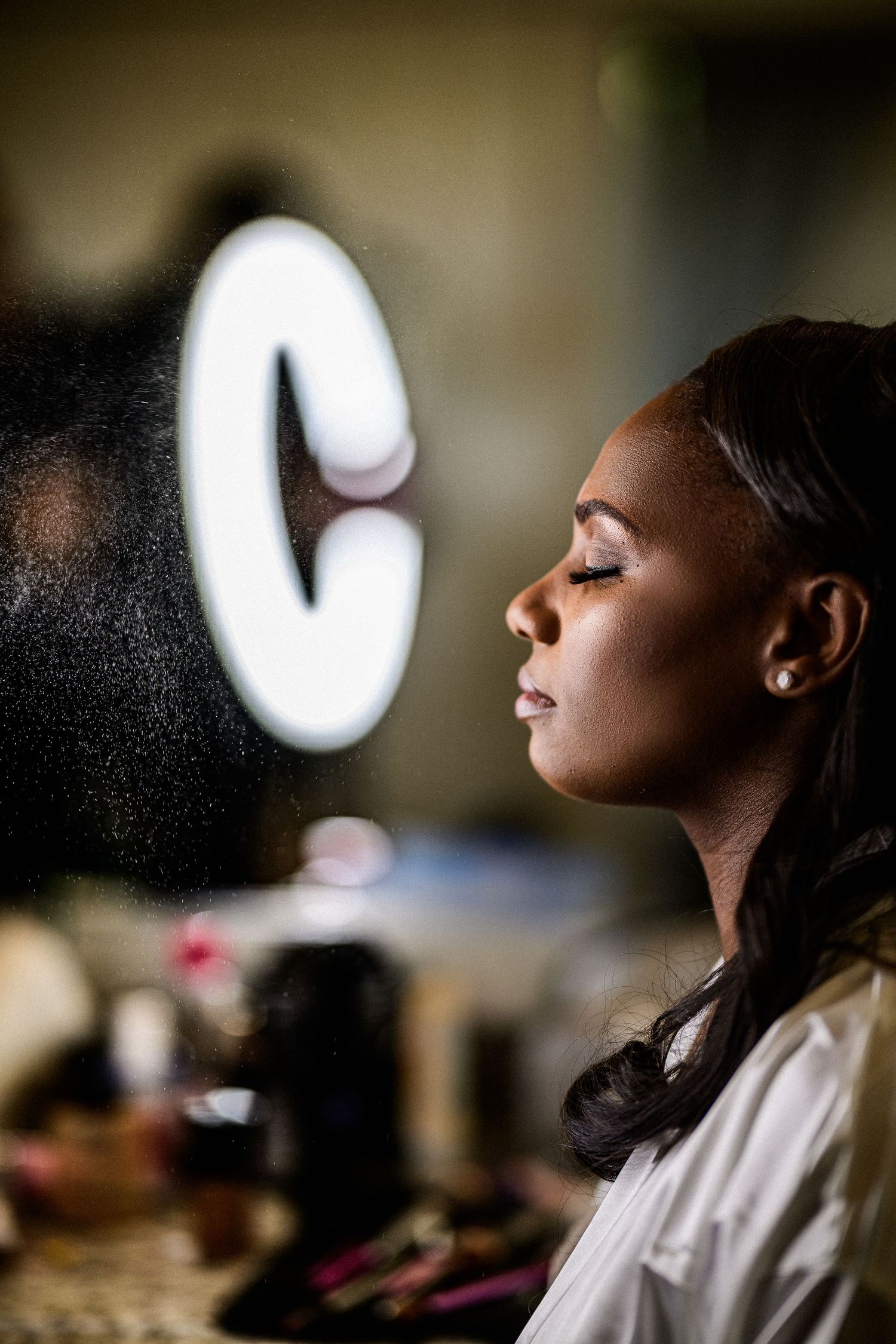 Artistic profile portrait in dramatic lighting showing elegant bridal makeup and hairstyle.