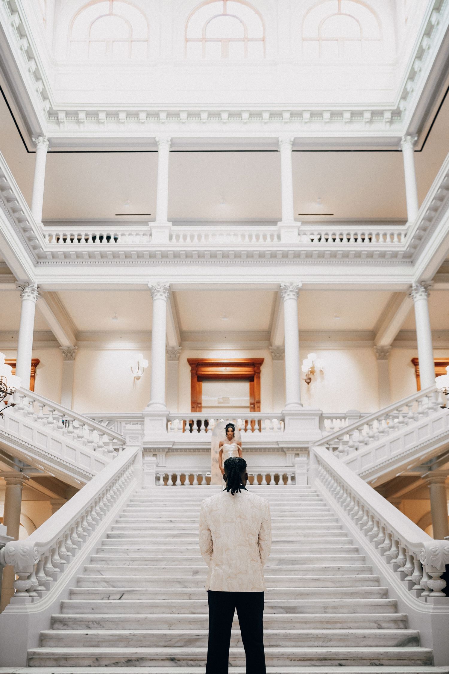 Elegant grand staircase with white marble columns and ornate architectural details in a historic building interior.