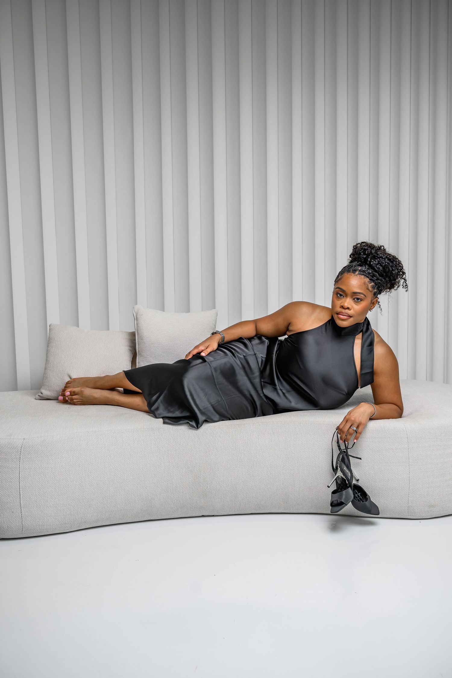 A sequence of artistic fashion photos featuring a person reclining on a white sofa in dark attire.