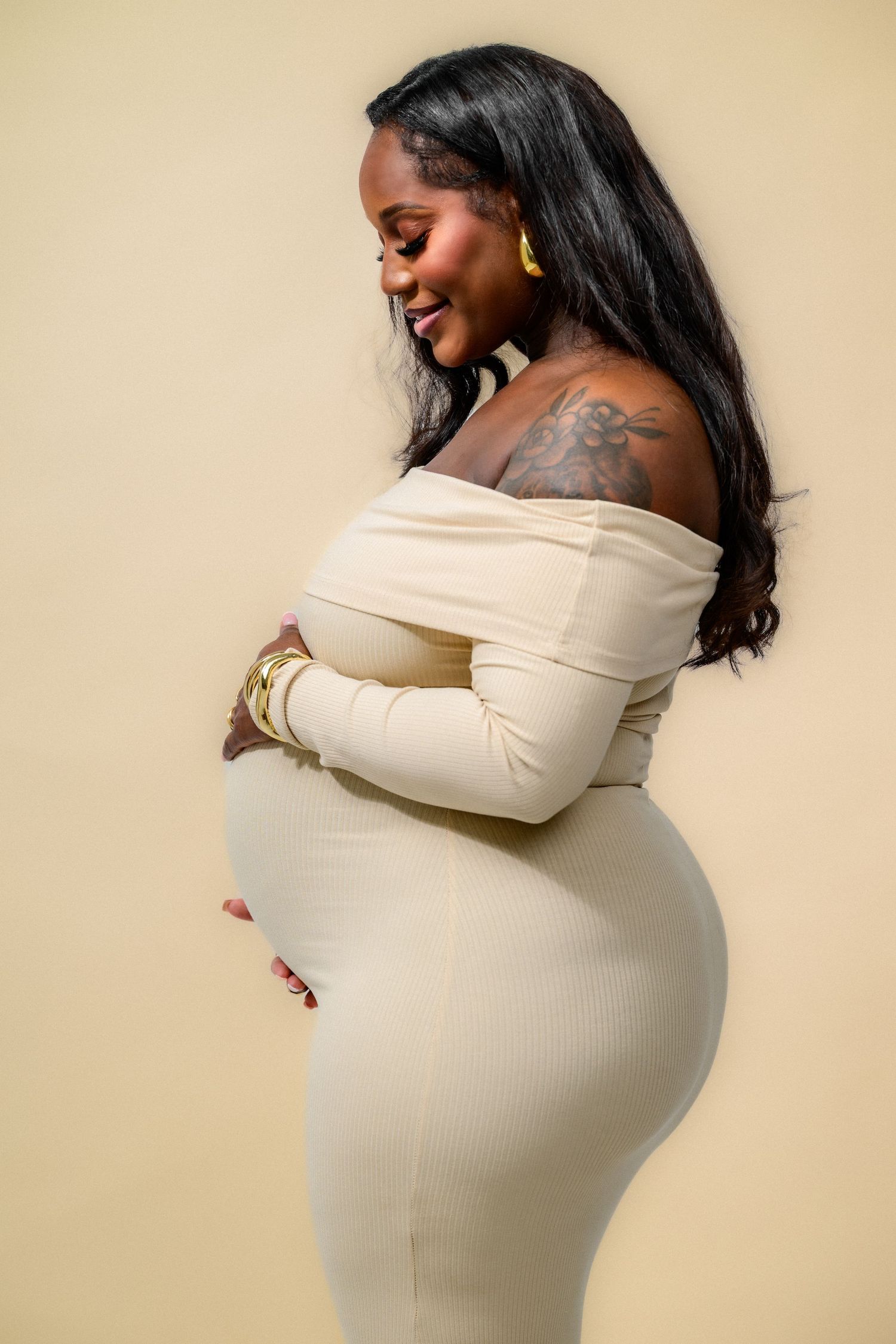 Side profile maternity portraits in cream fitted dress showing pregnancy silhouette.