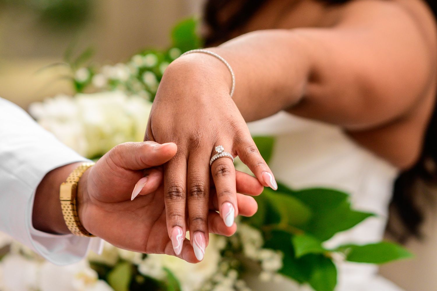 Close-up of hands holding delicate greenery during wedding photoshoot.