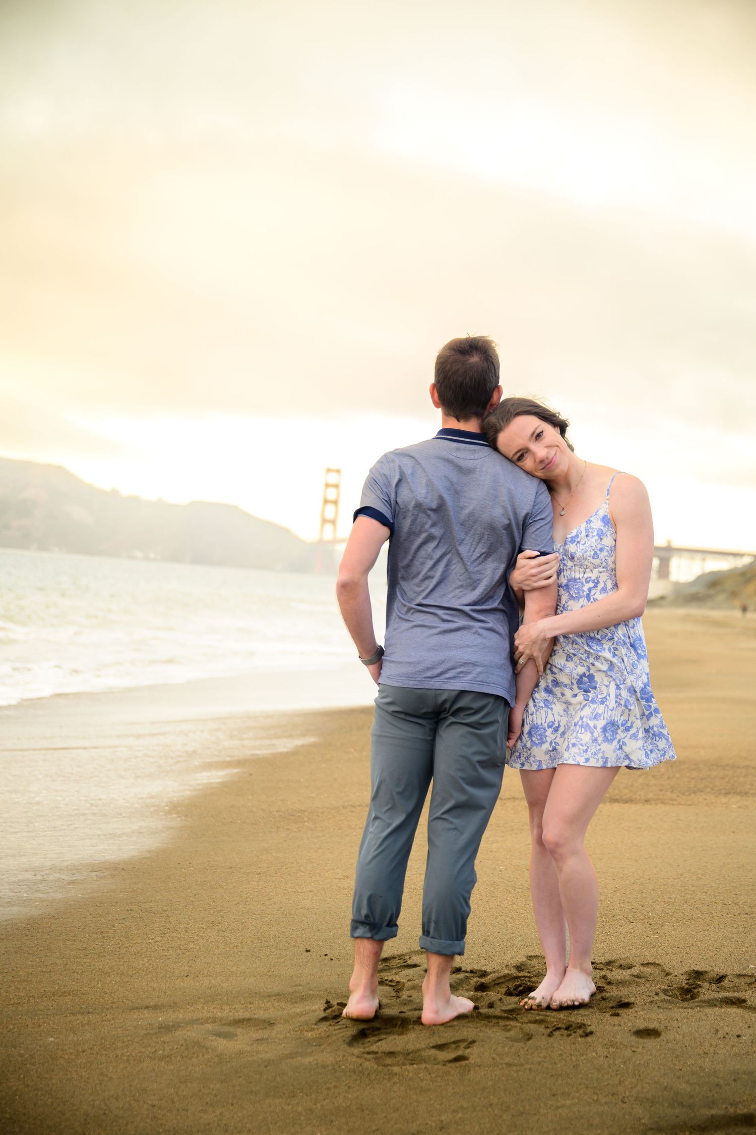 A couple walks together on a misty beach at sunset, creating a romantic silhouette.