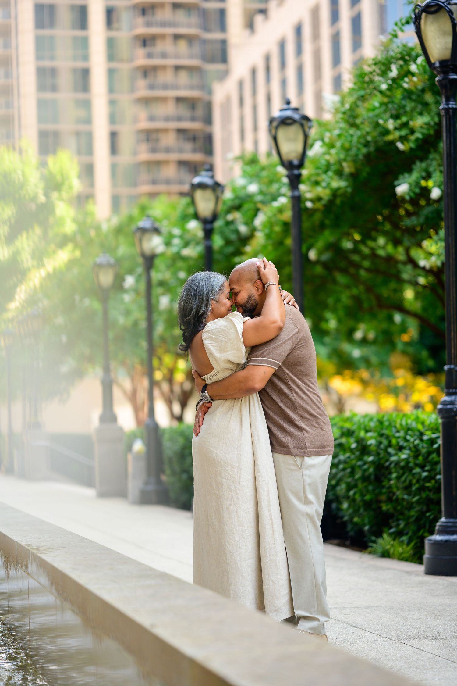 Couple sharing romantic moments along an urban walkway with lamp posts.