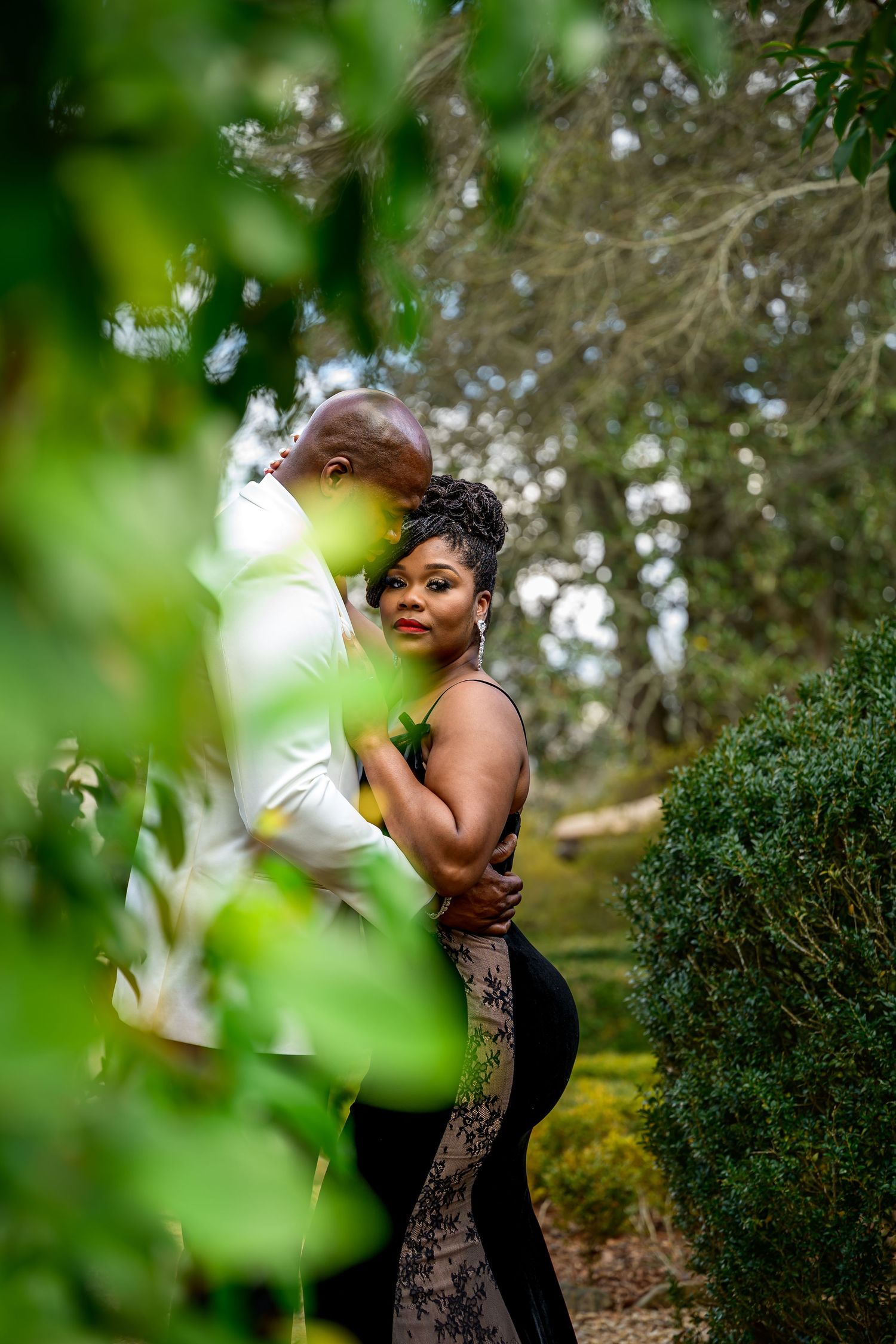 A romantic outdoor photoshoot in a lush garden setting with green foliage and natural lighting.