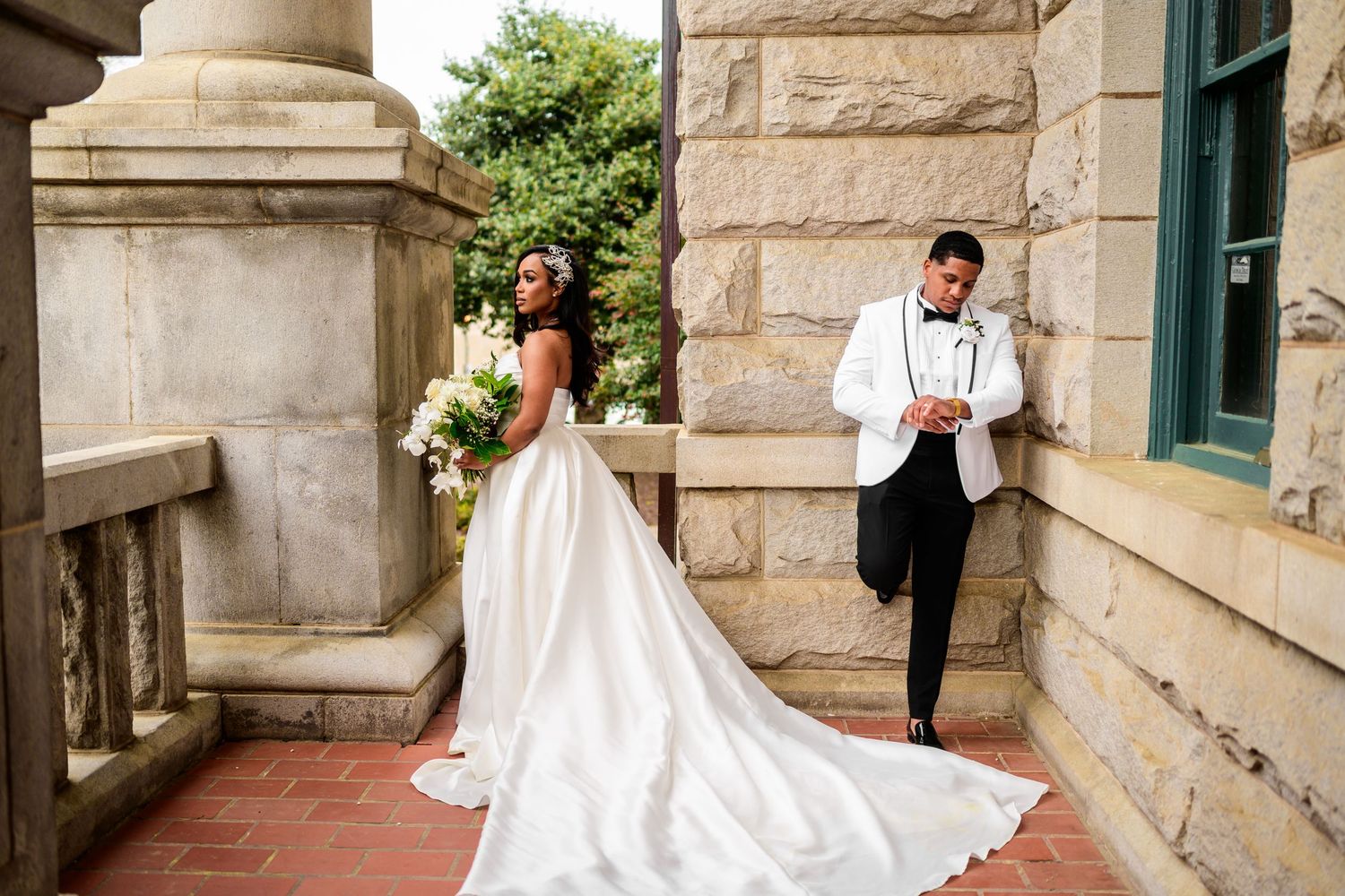 Wedding couple creates romantic poses along stone building exterior.
