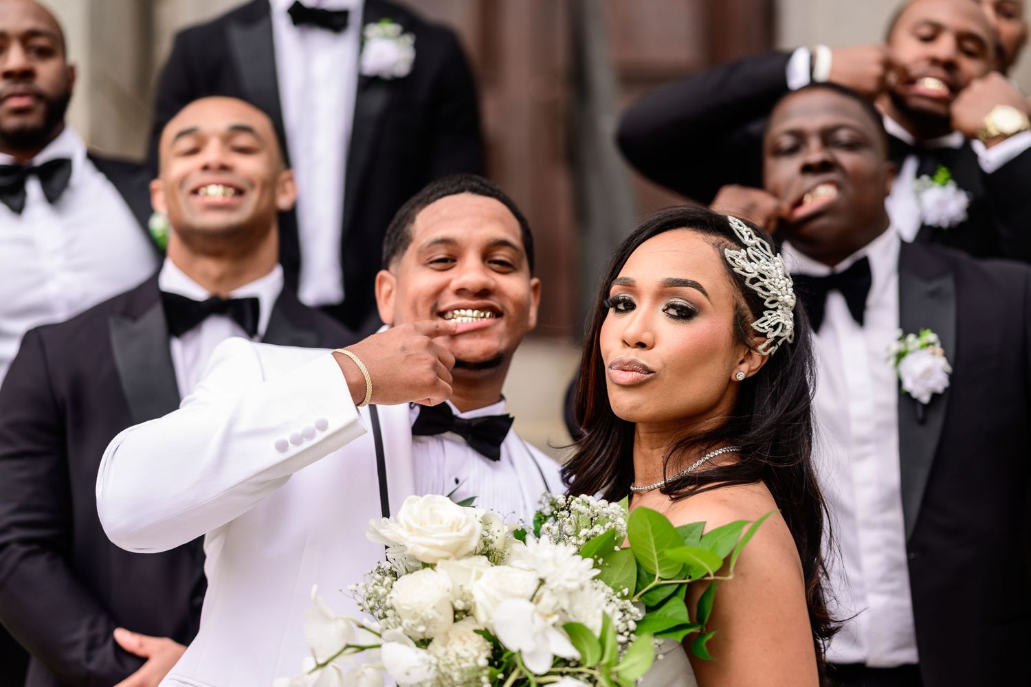 Wedding party shares joyful candid moments outside historic venue.