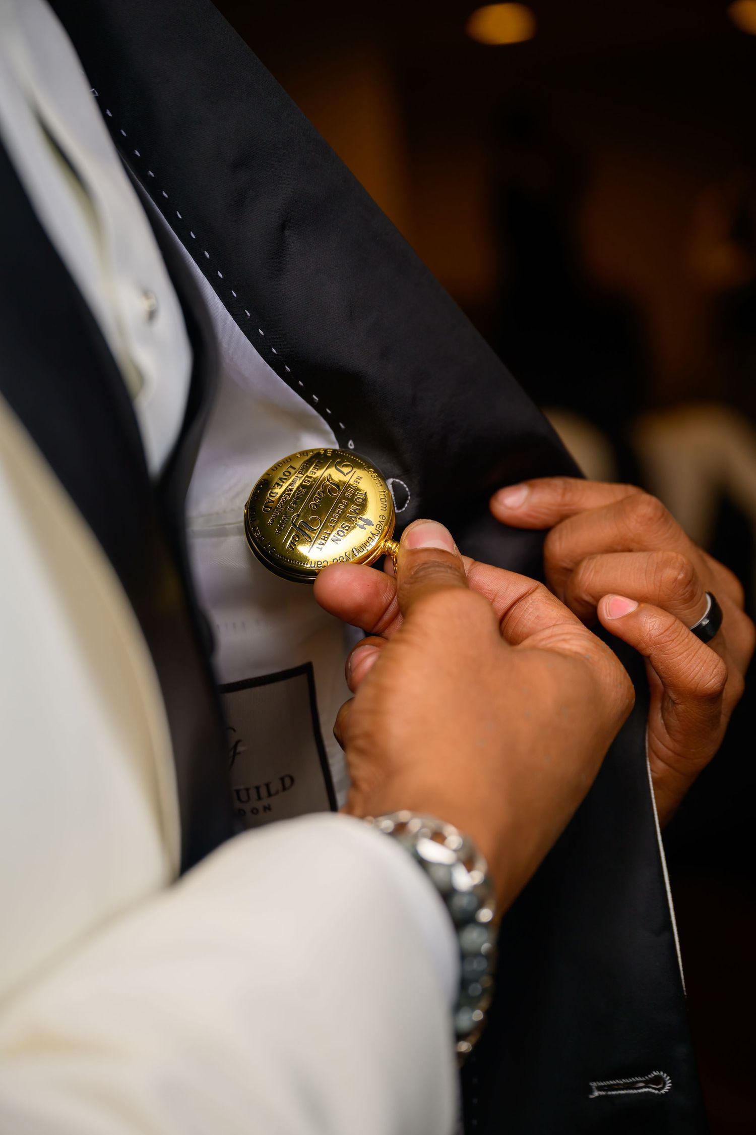 Close-up shot of hands adjusting a gold pocket watch against formal black and white attire.