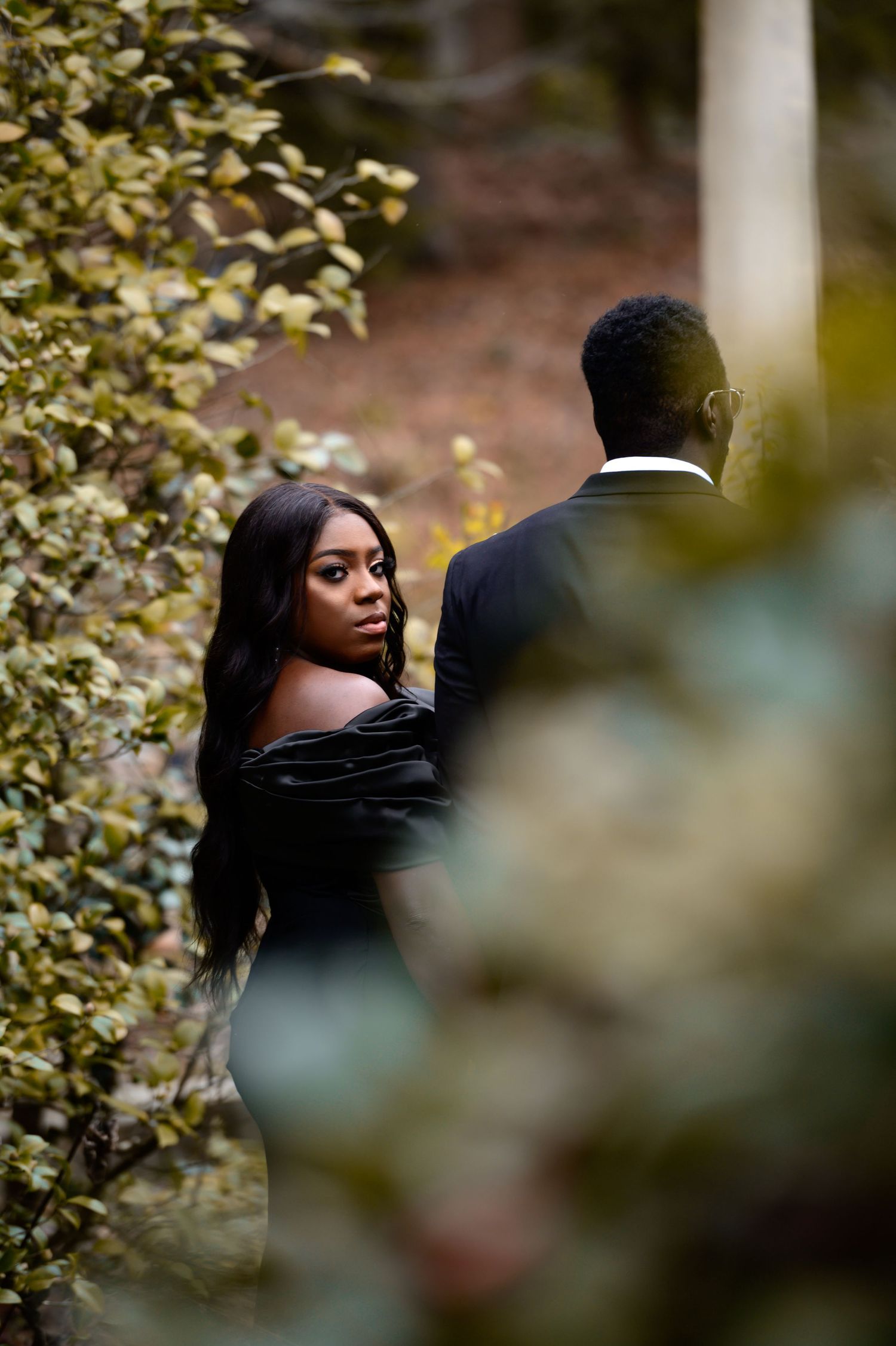 Artistic portrait through leaves showing a couple in an intimate outdoor moment.