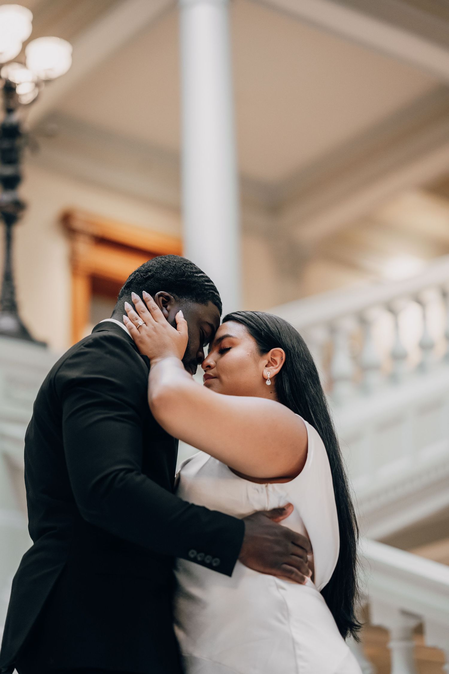 Intimate moment between newlyweds in formal attire by classical white columns.