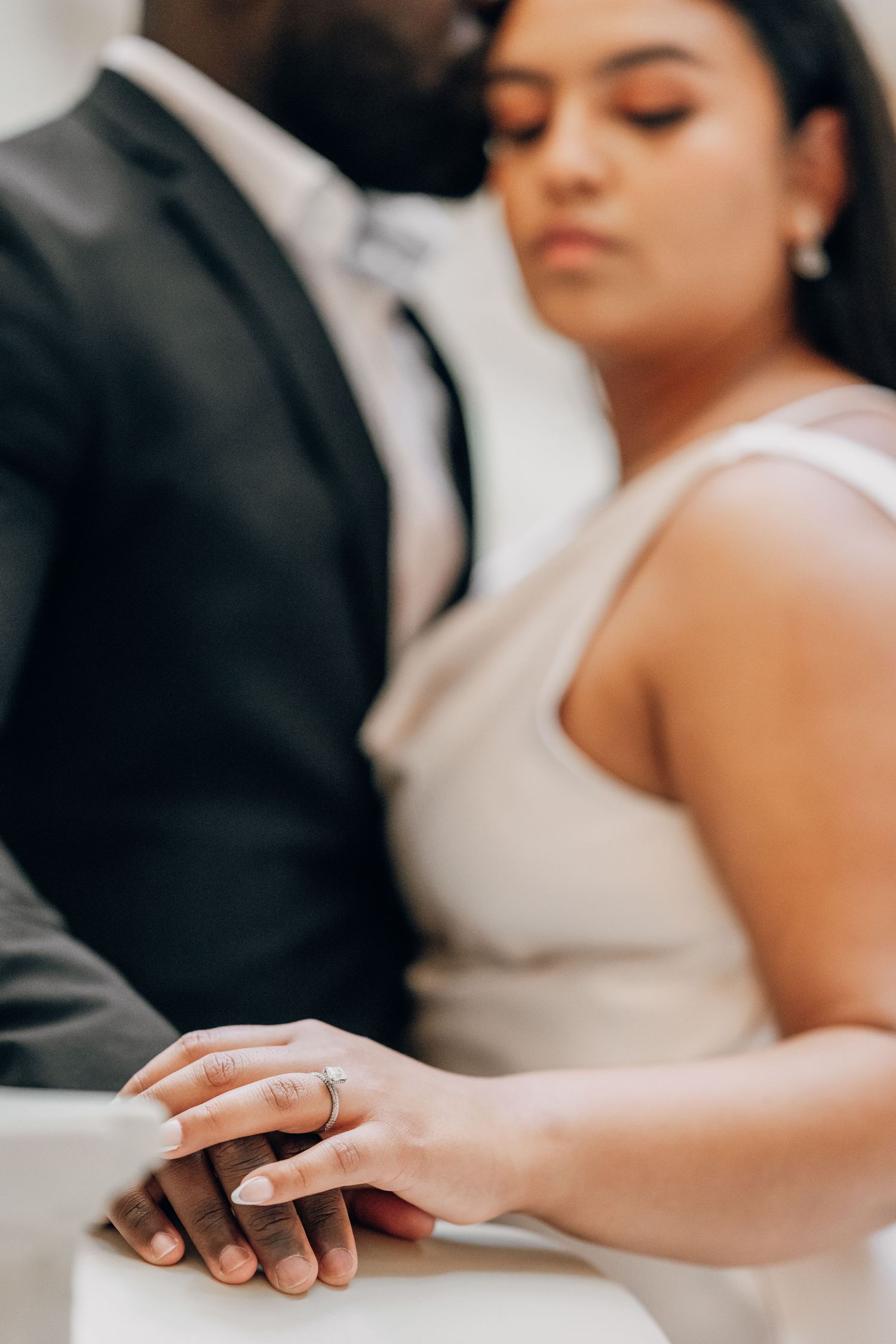 Close-up of hands and wedding rings during intimate moment.
