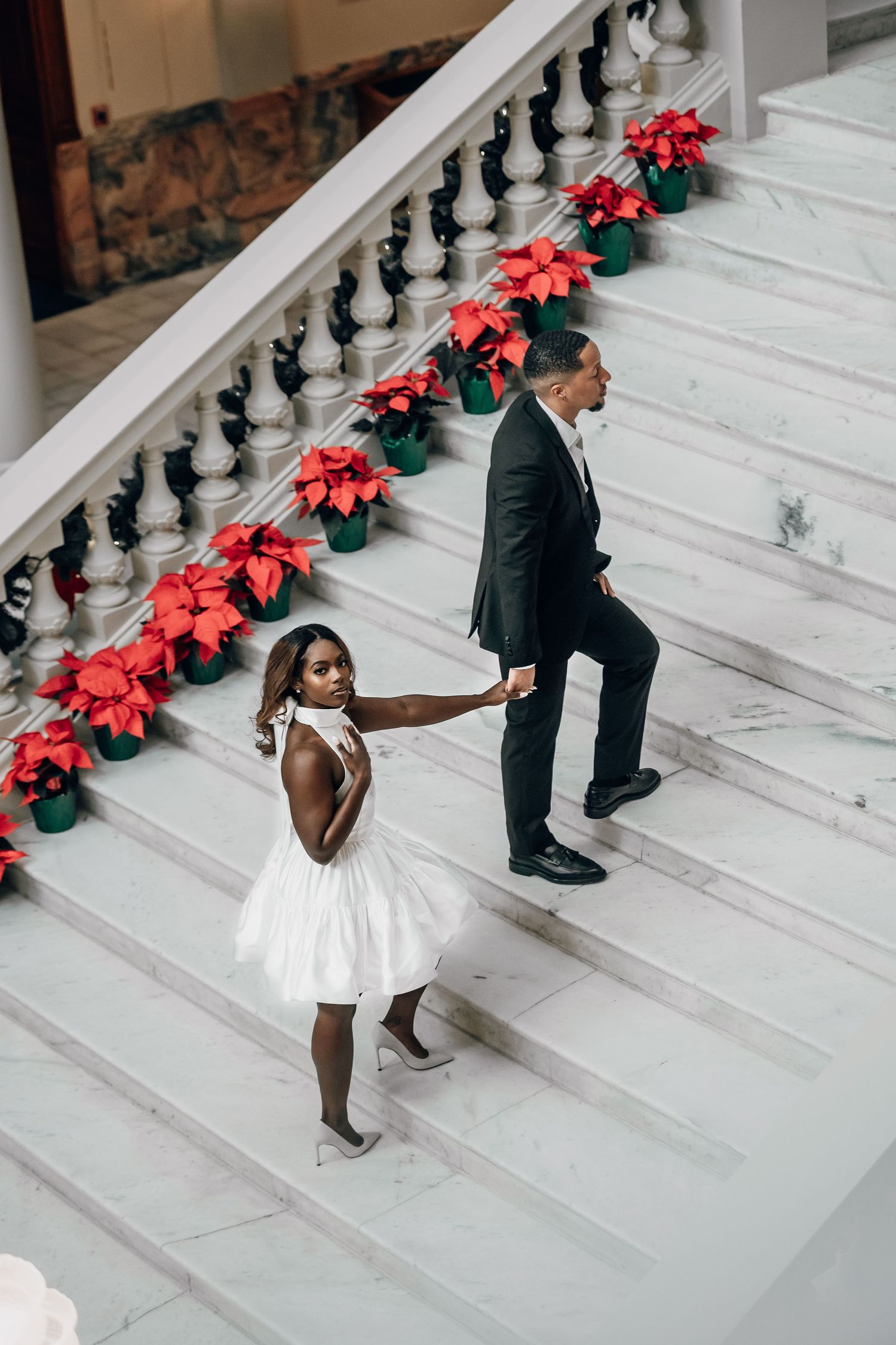 Playful dance sequence on white marble steps decorated with red poinsettias.