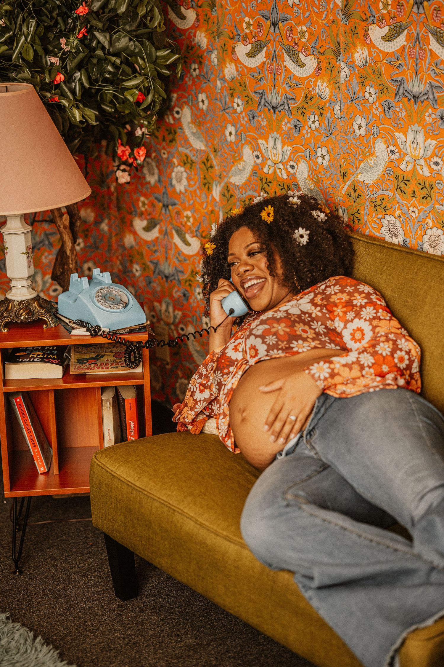 Vintage-inspired photoshoot against orange wallpaper featuring a cozy mustard yellow sofa.