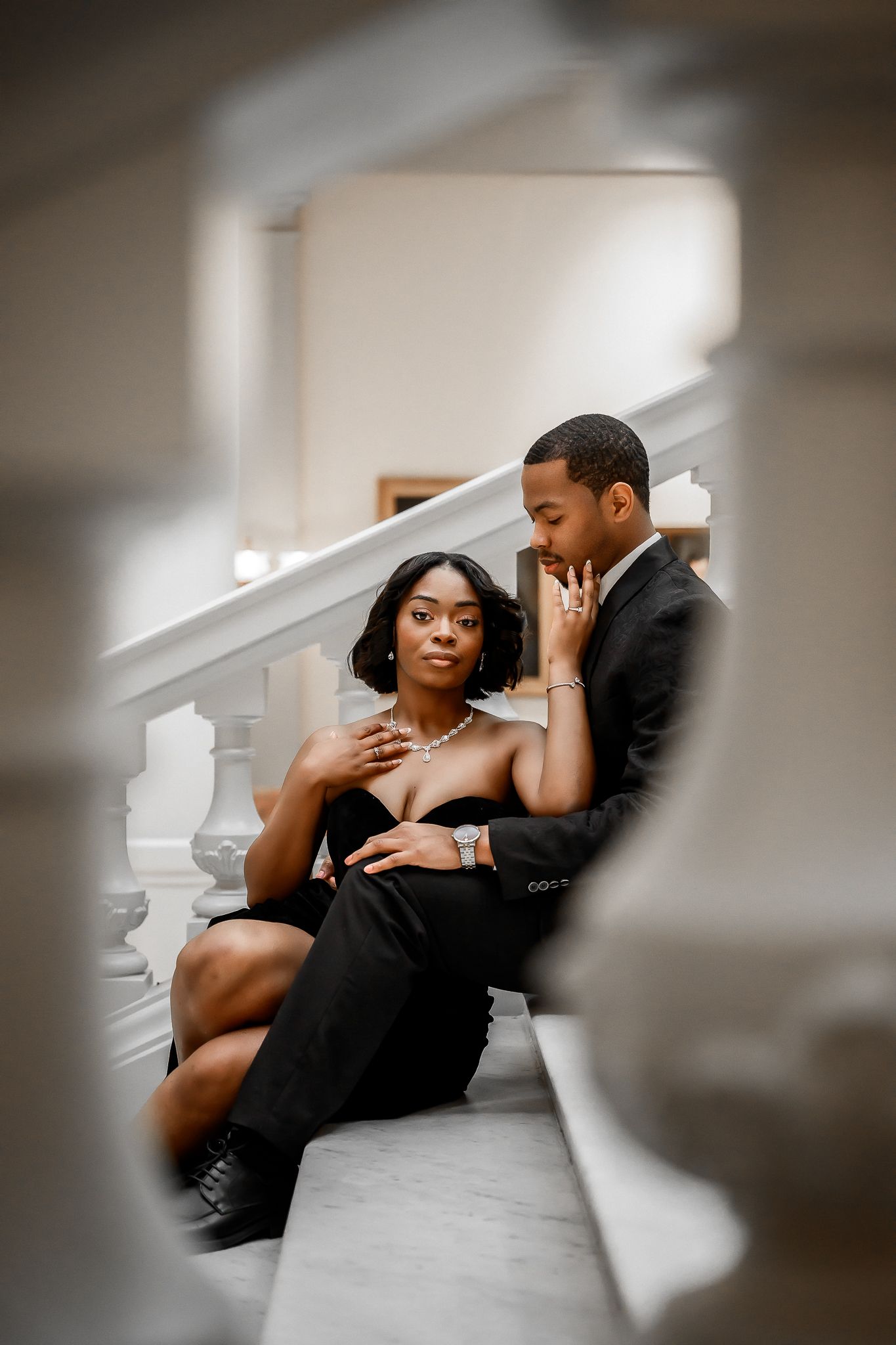 Intimate couple portrait on marble stairs with artistic lighting and composition.