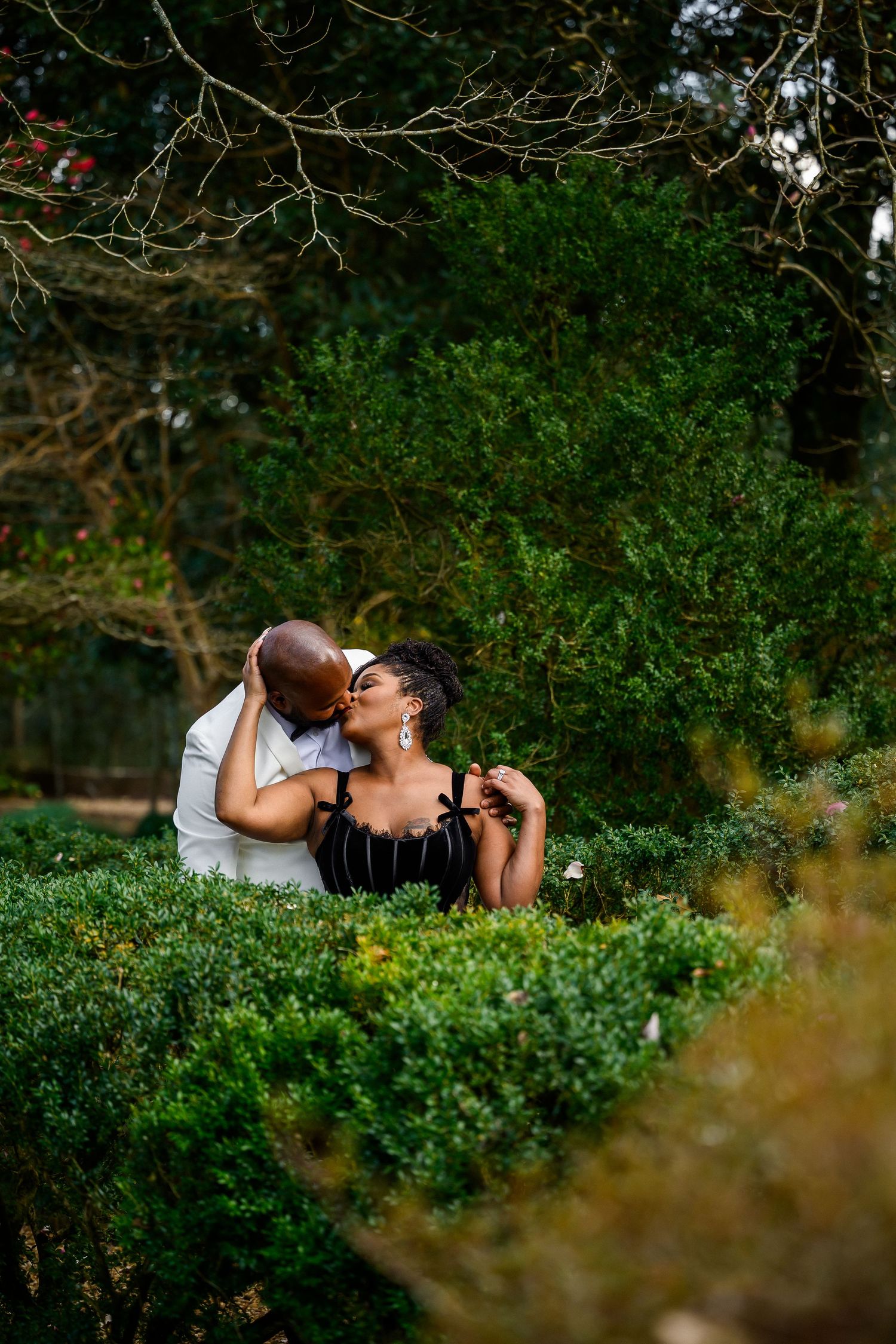 A romantic couple shares an intimate moment while sitting together in a lush garden setting during golden hour.