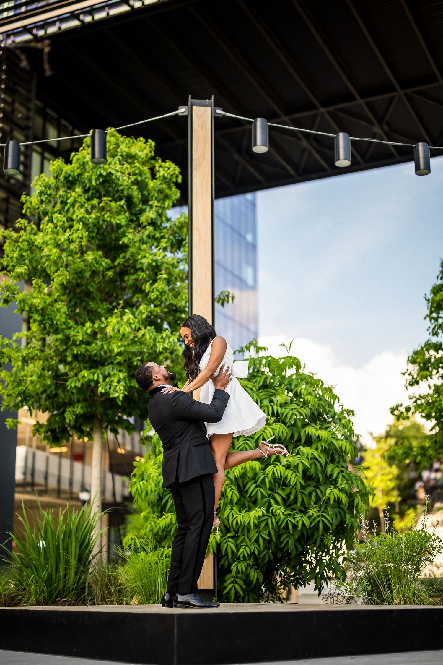 Silhouetted figures dance under an outdoor pavilion surrounded by greenery.