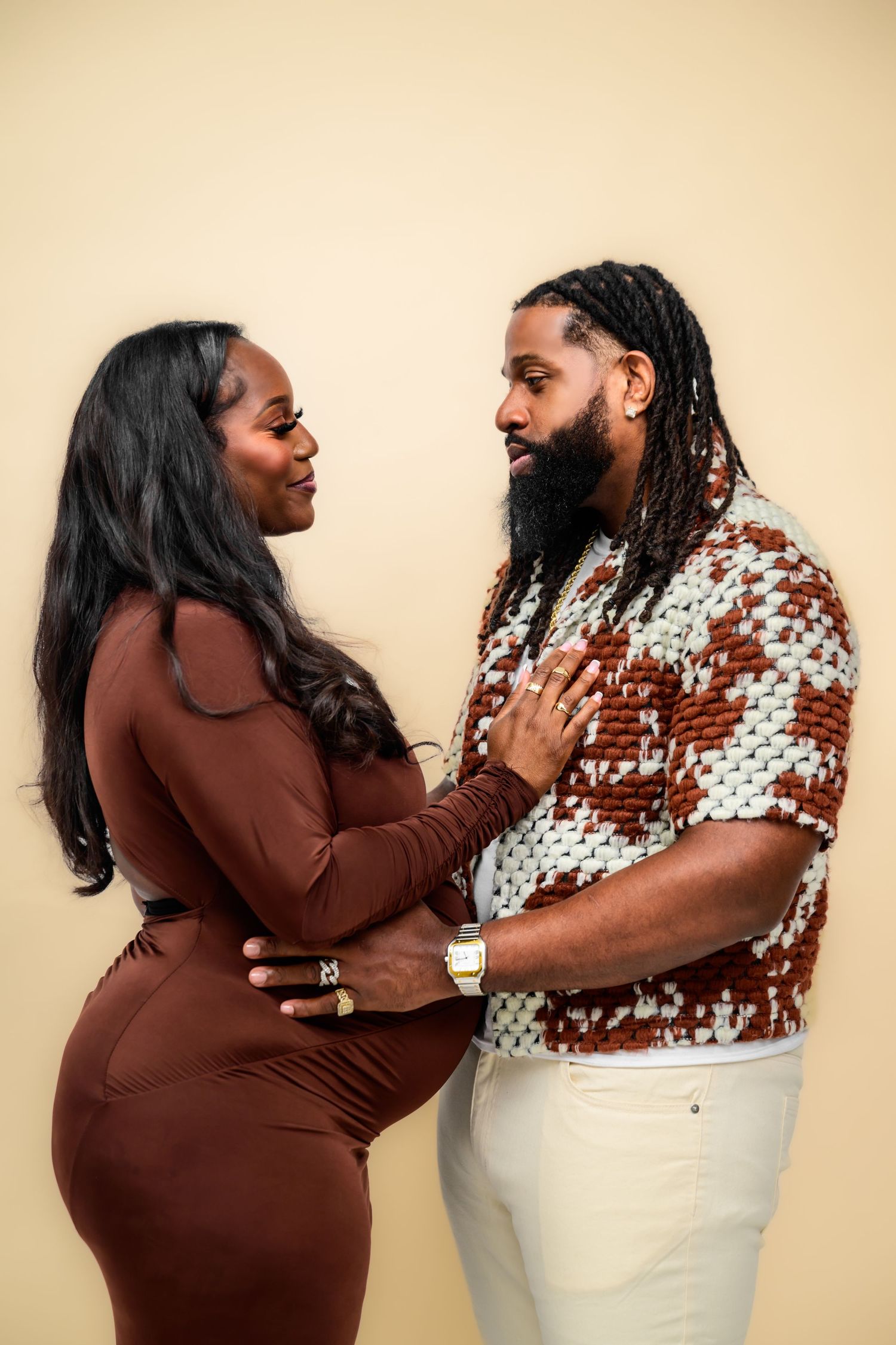 Intimate maternity photos showing tender moments between a couple in matching brown and white outfits.