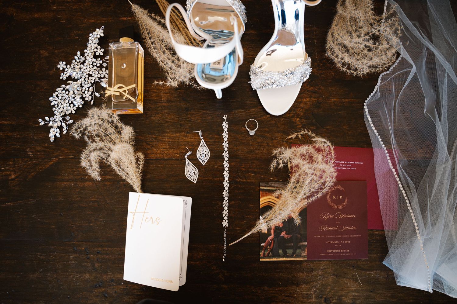 Wedding details including white veil and decorative elements arranged on dark wooden surface.