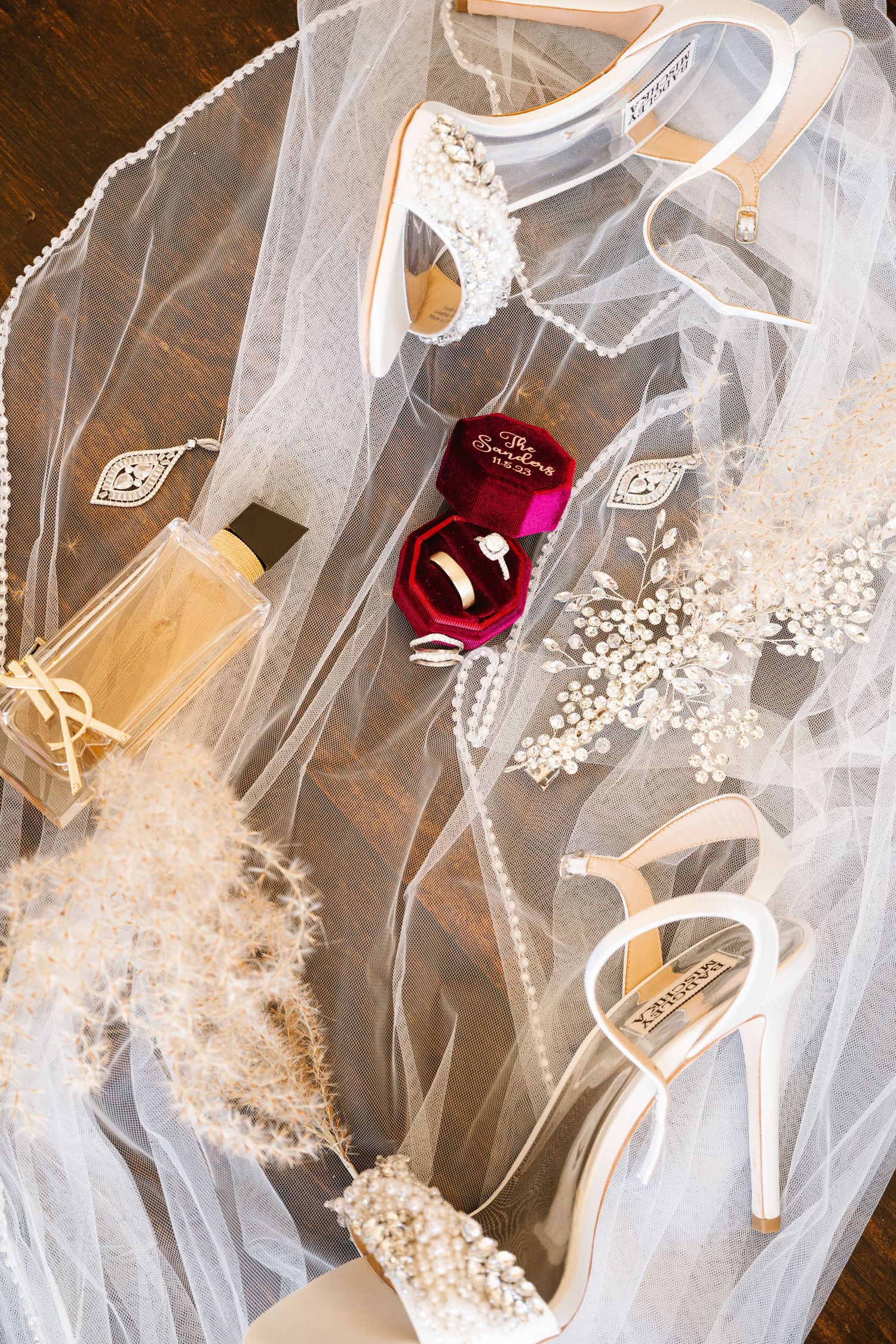 Delicate white wedding veil with lace details and pearl embellishments on wooden surface.