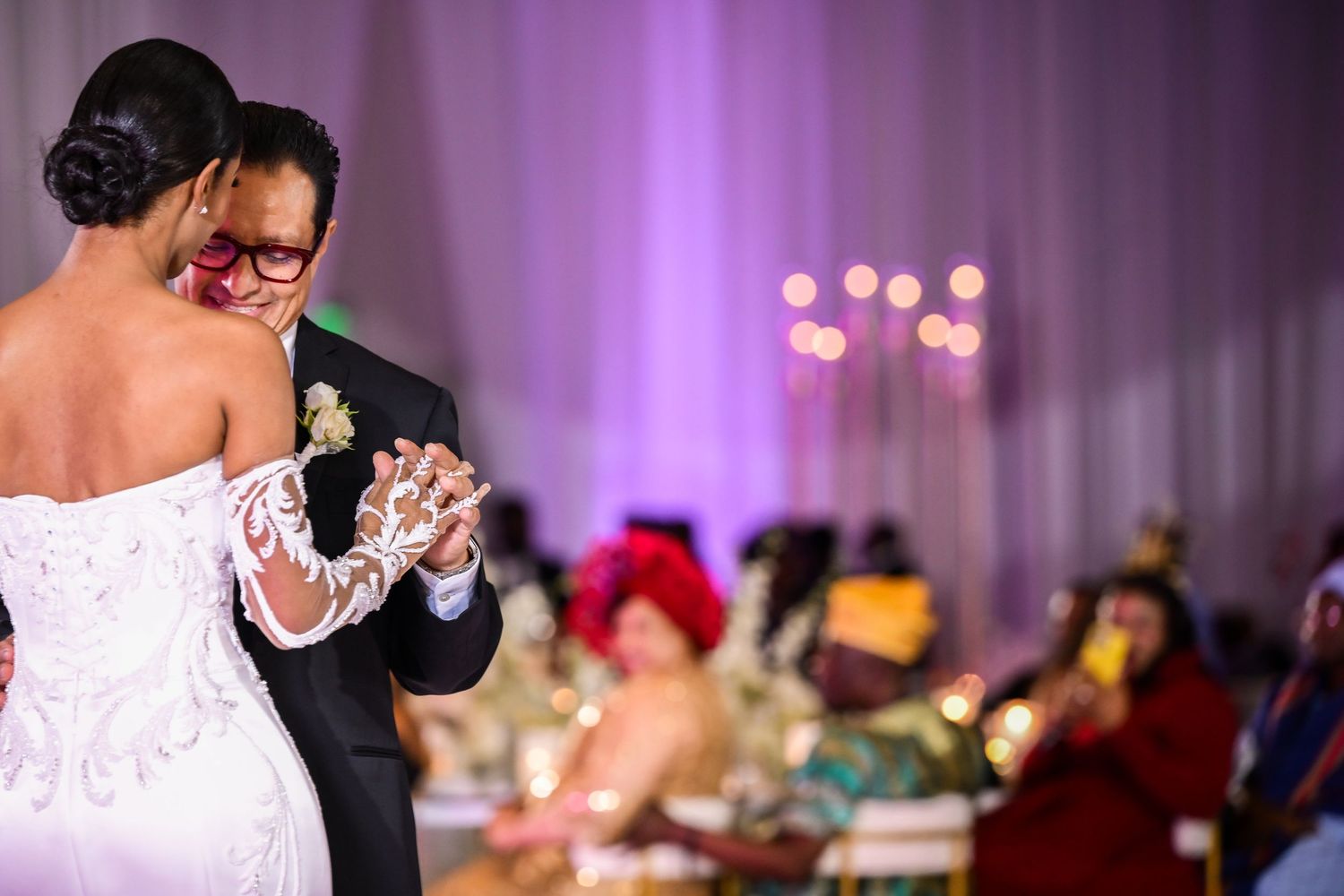 Wedding reception dance floor with romantic purple lighting and white draping.