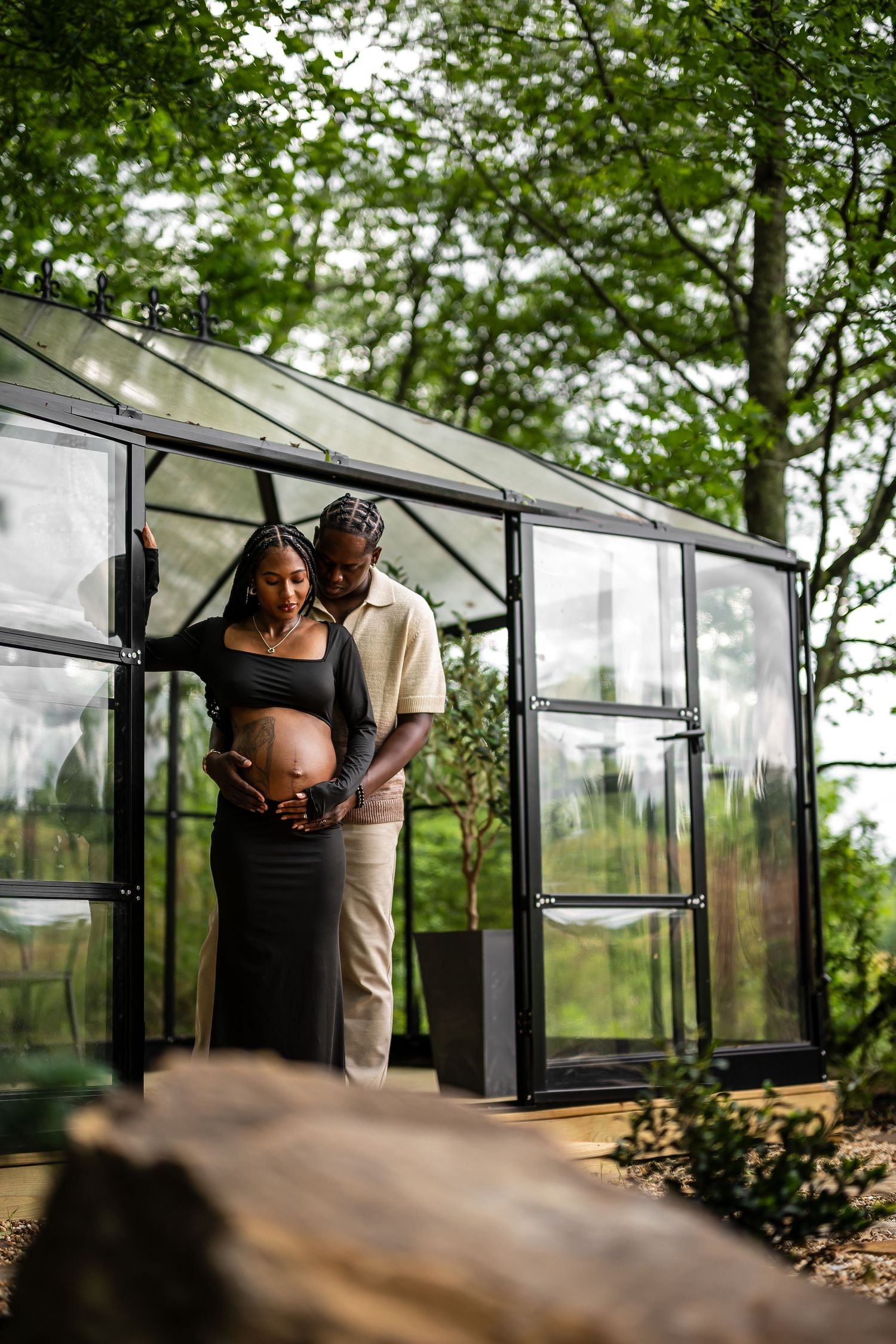 A tender moment captured inside a glass greenhouse surrounded by natural greenery.