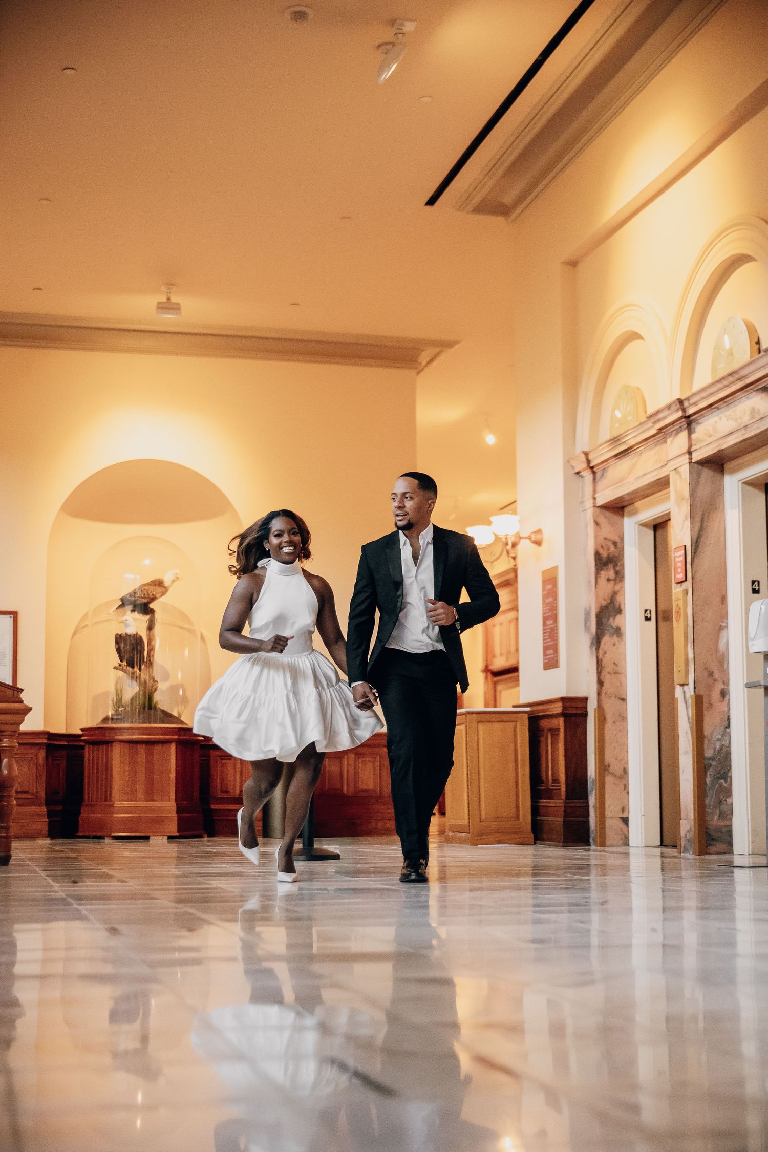 Dynamic dance sequence in an elegant hallway with marble floors and warm lighting.