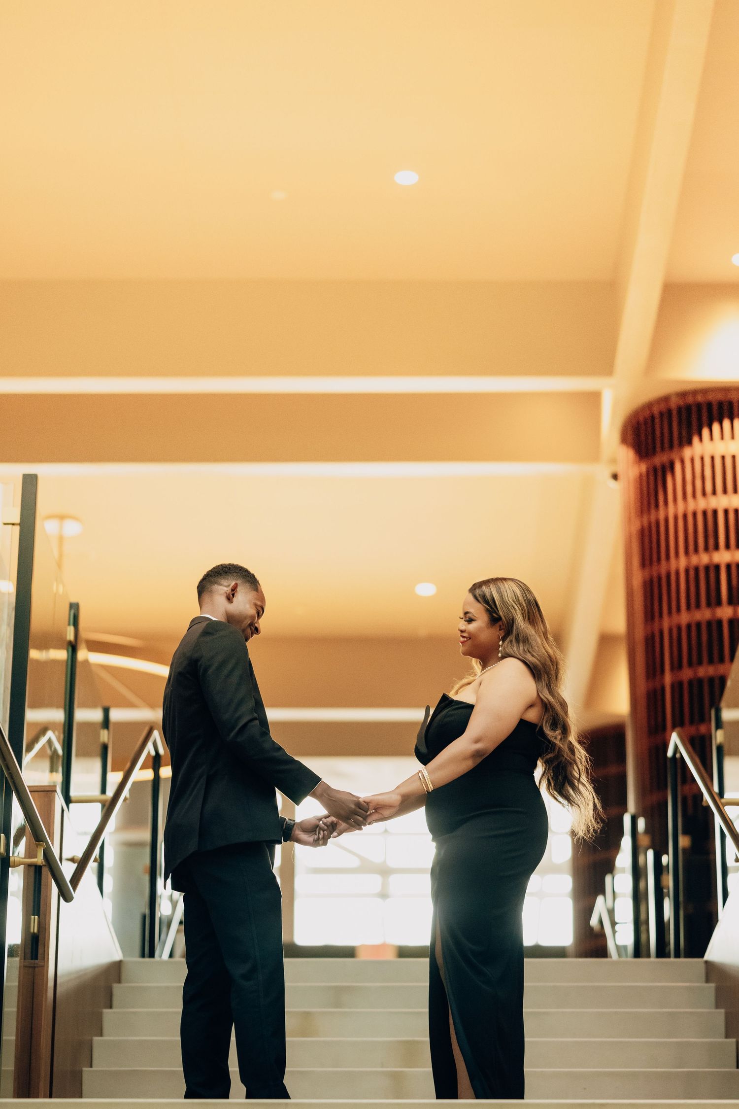 Romantic couple interacting on stairs in an upscale venue with warm lighting.