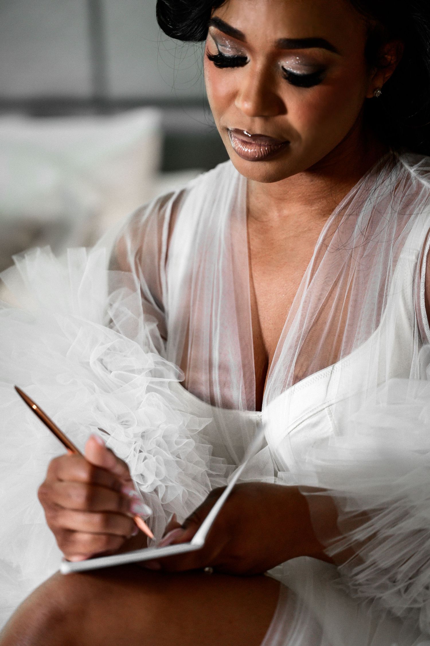 Intimate bridal portrait with white tulle robe while writing.