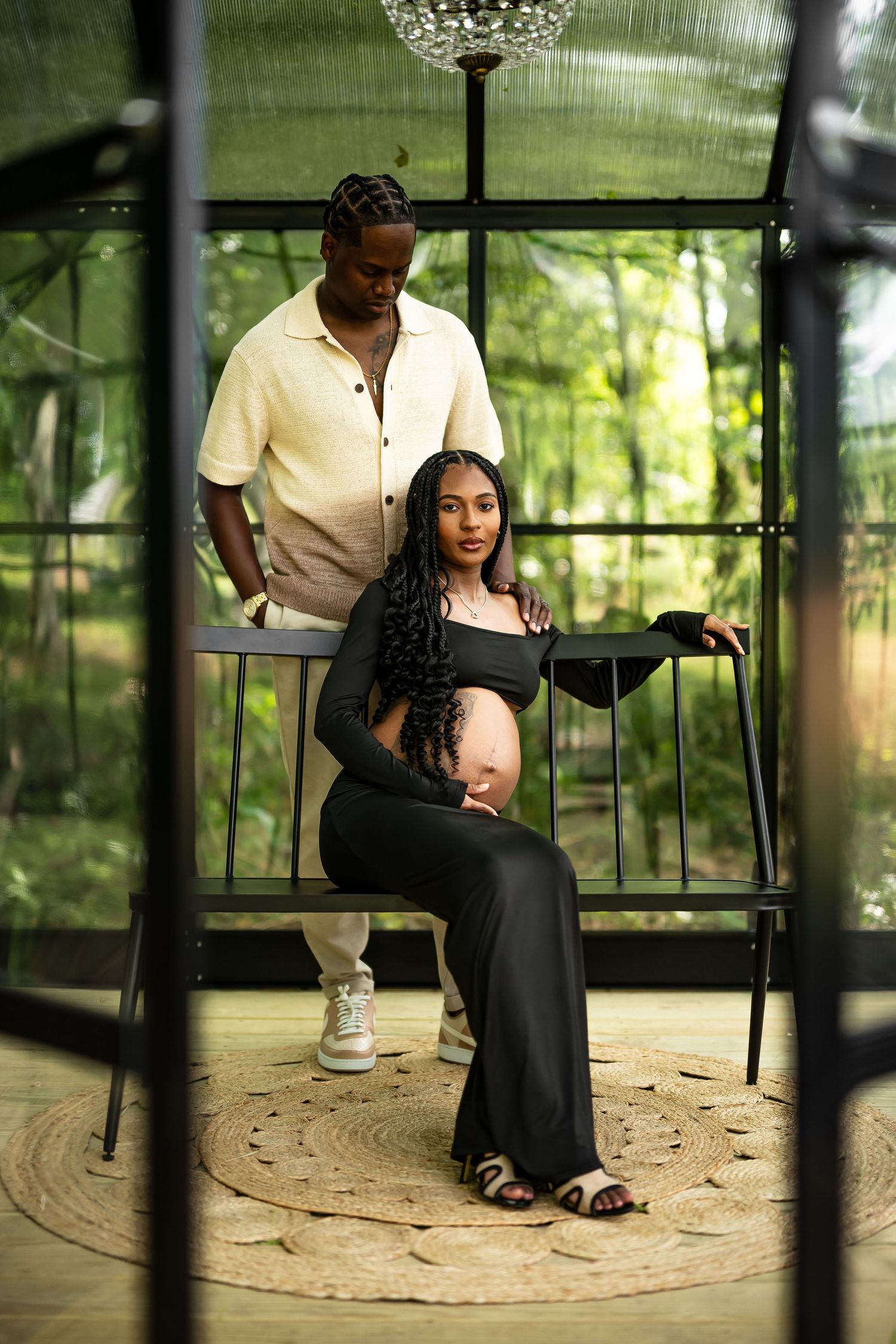 A romantic maternity session unfolds in a glass greenhouse with hanging crystal chandelier.