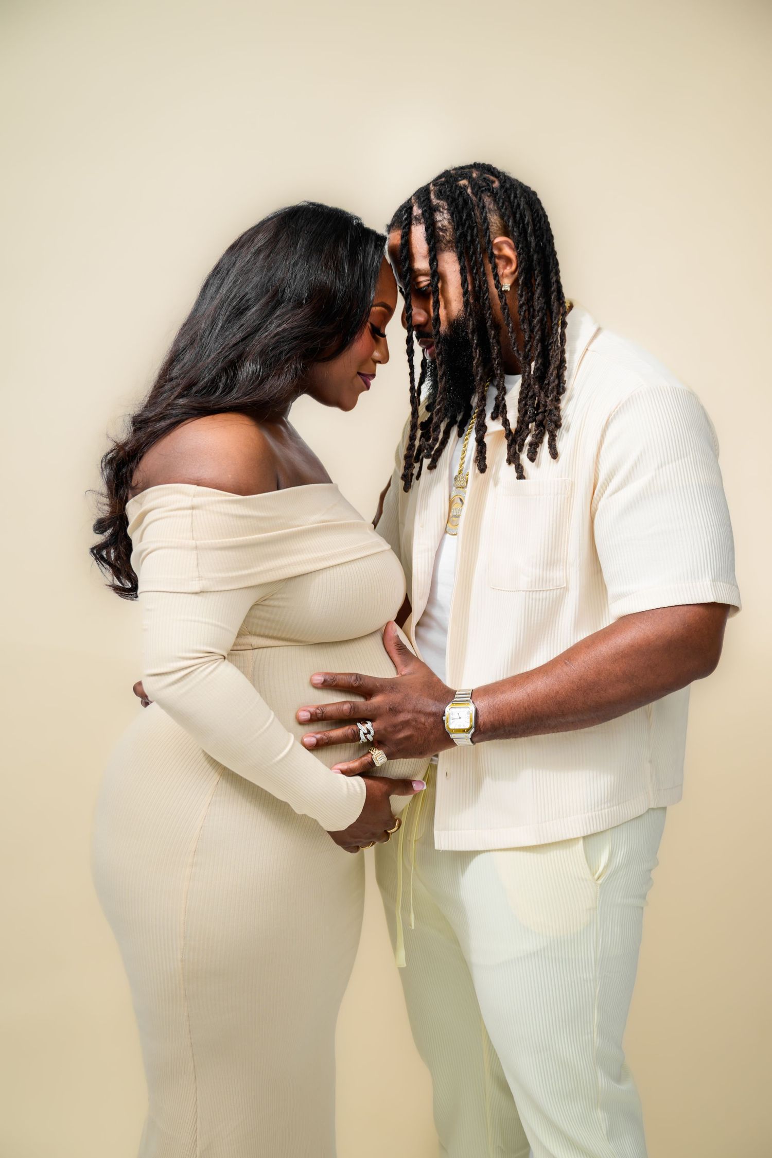 Intimate maternity poses captured in studio with couple wearing coordinated white outfits.