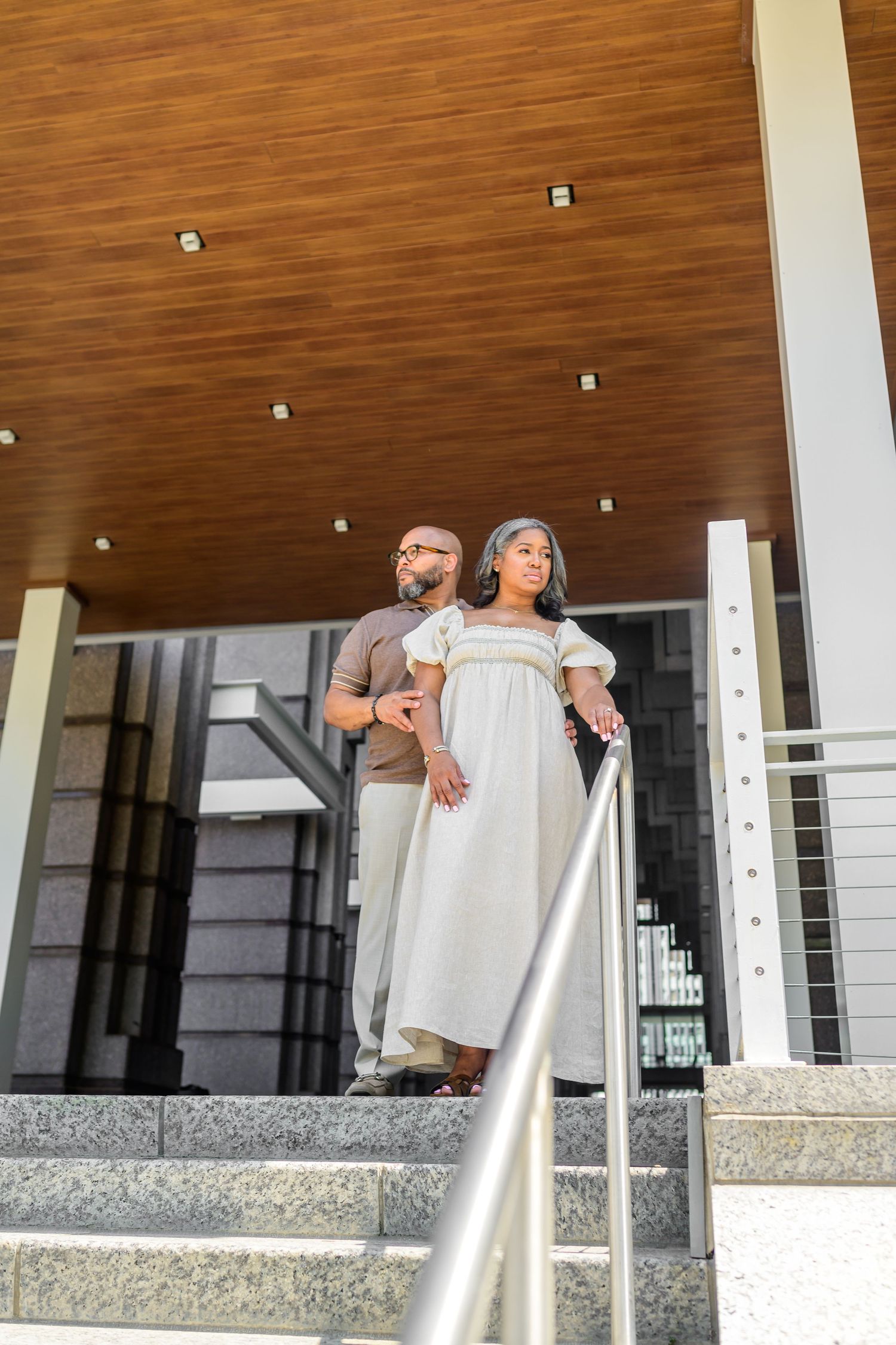 Modern architectural interior with wood ceiling and metal railings serves as engagement photo backdrop.