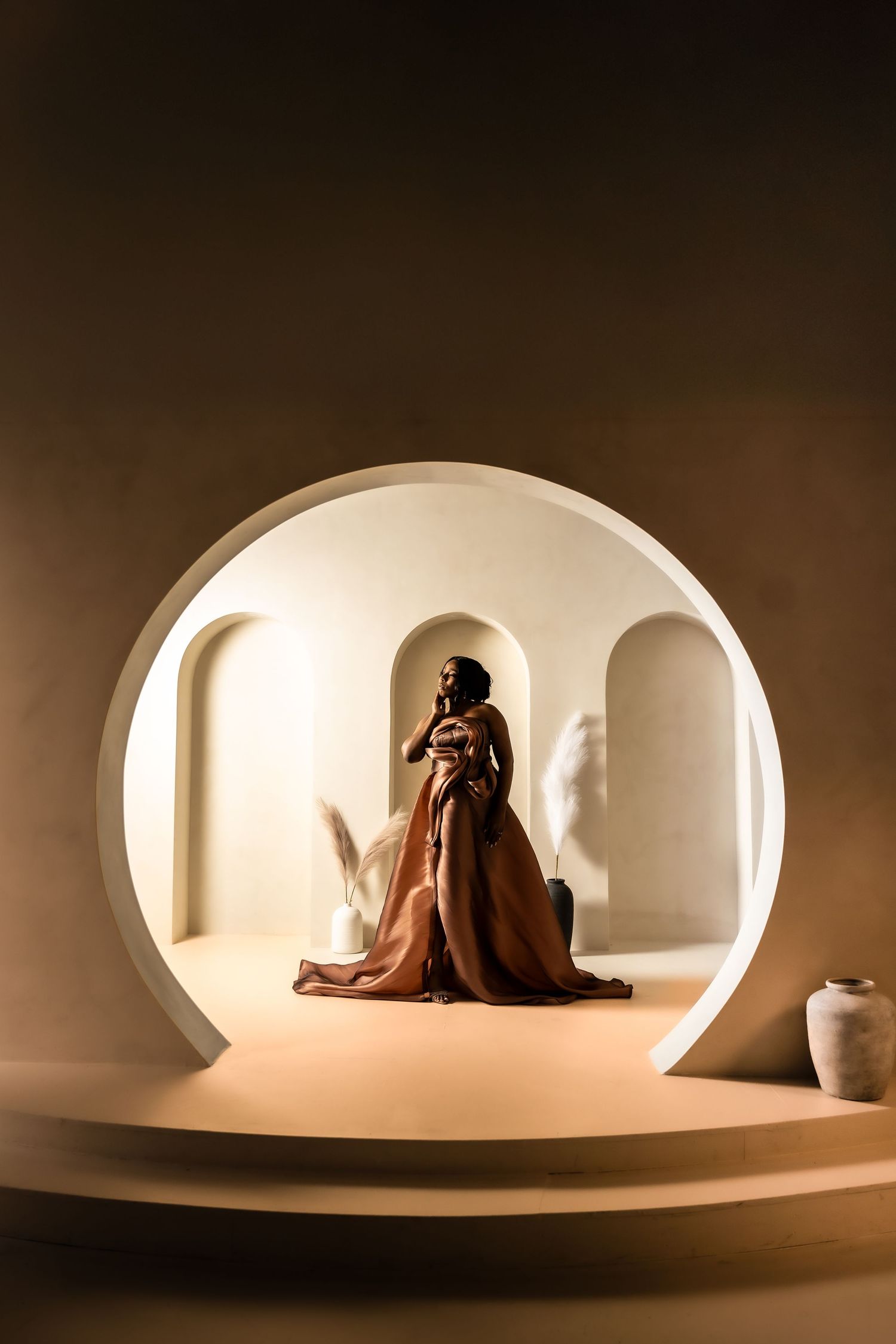 Artistic silhouette photography in a curved white architectural space with dramatic lighting.